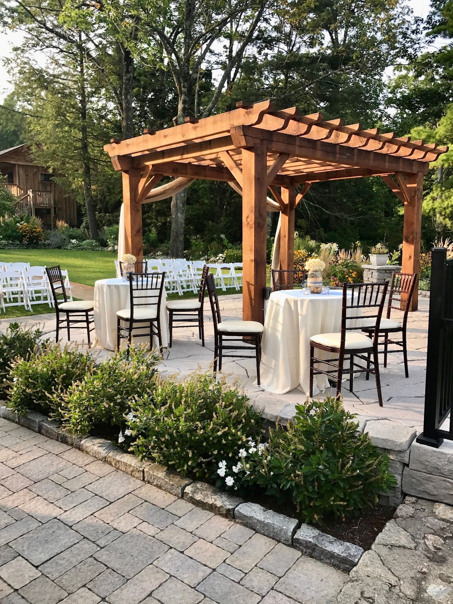 A wooden pergola with tables and chairs underneath it.