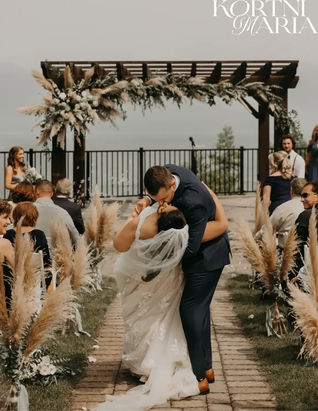 A bride and groom are kissing at their wedding ceremony.