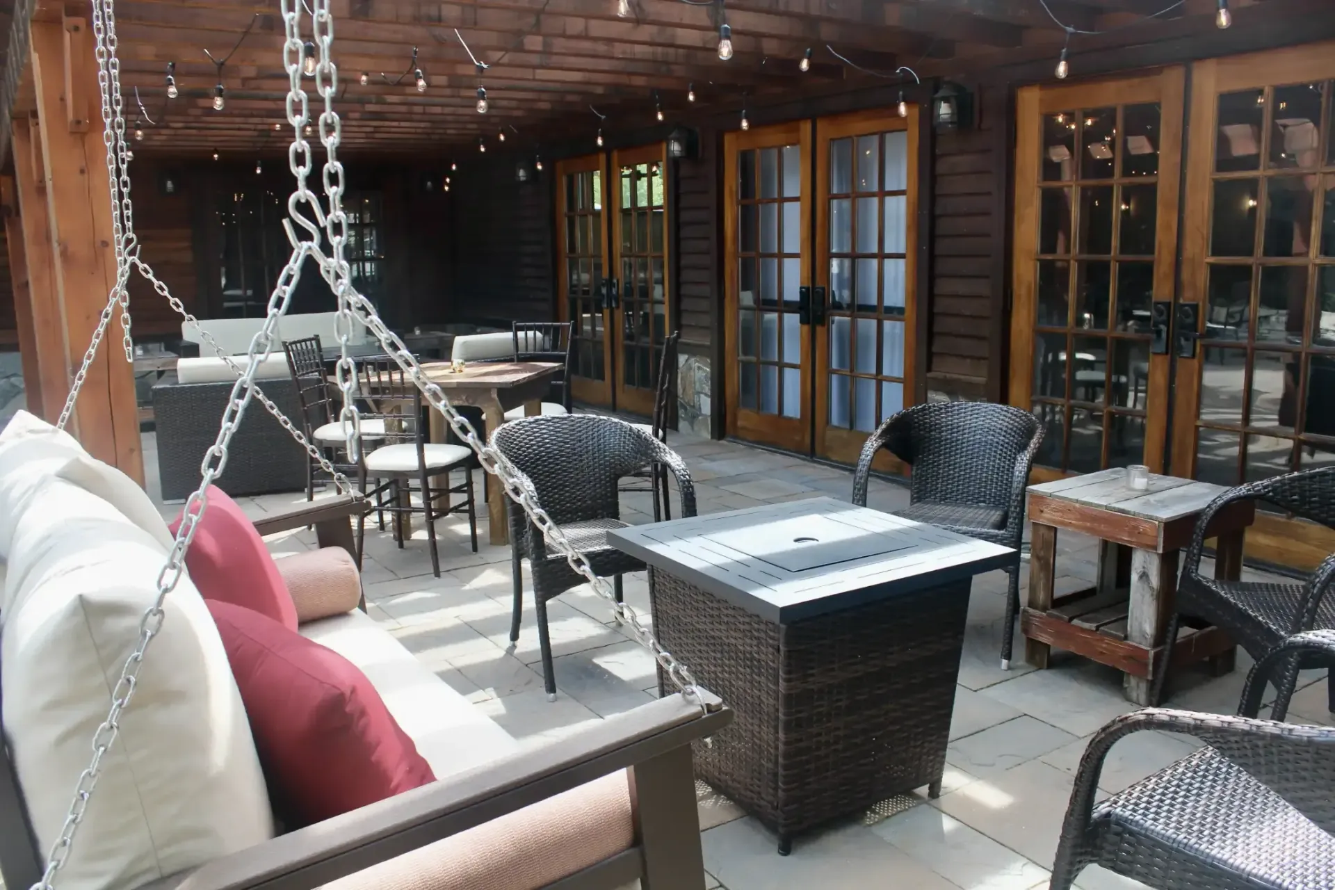 A patio with wicker furniture including a swing and a table