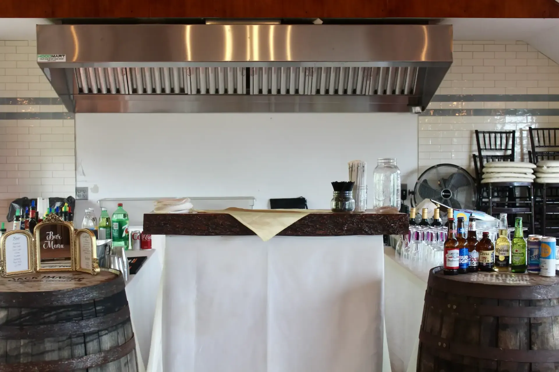 A kitchen with a stainless steel hood and barrels filled with alcohol.