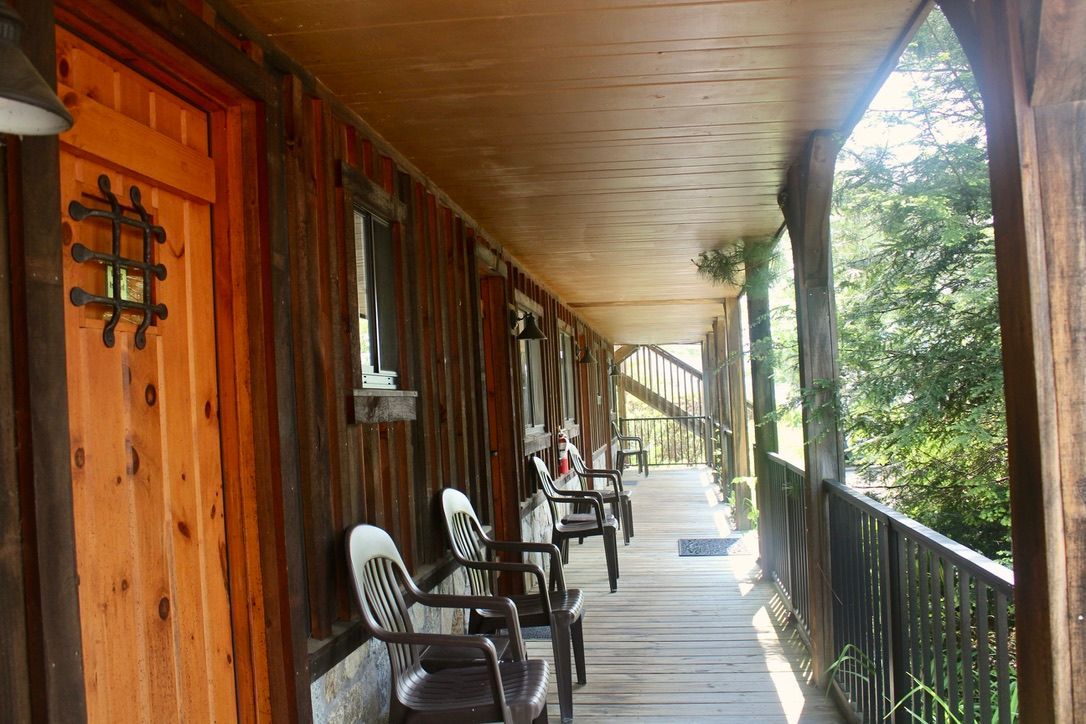 A long wooden porch with chairs and a wooden door