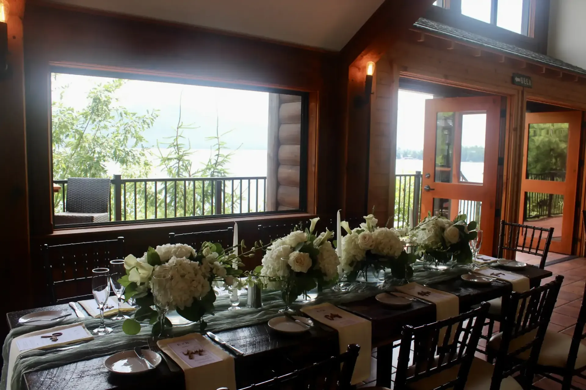 A long table with flowers on it in front of a window.