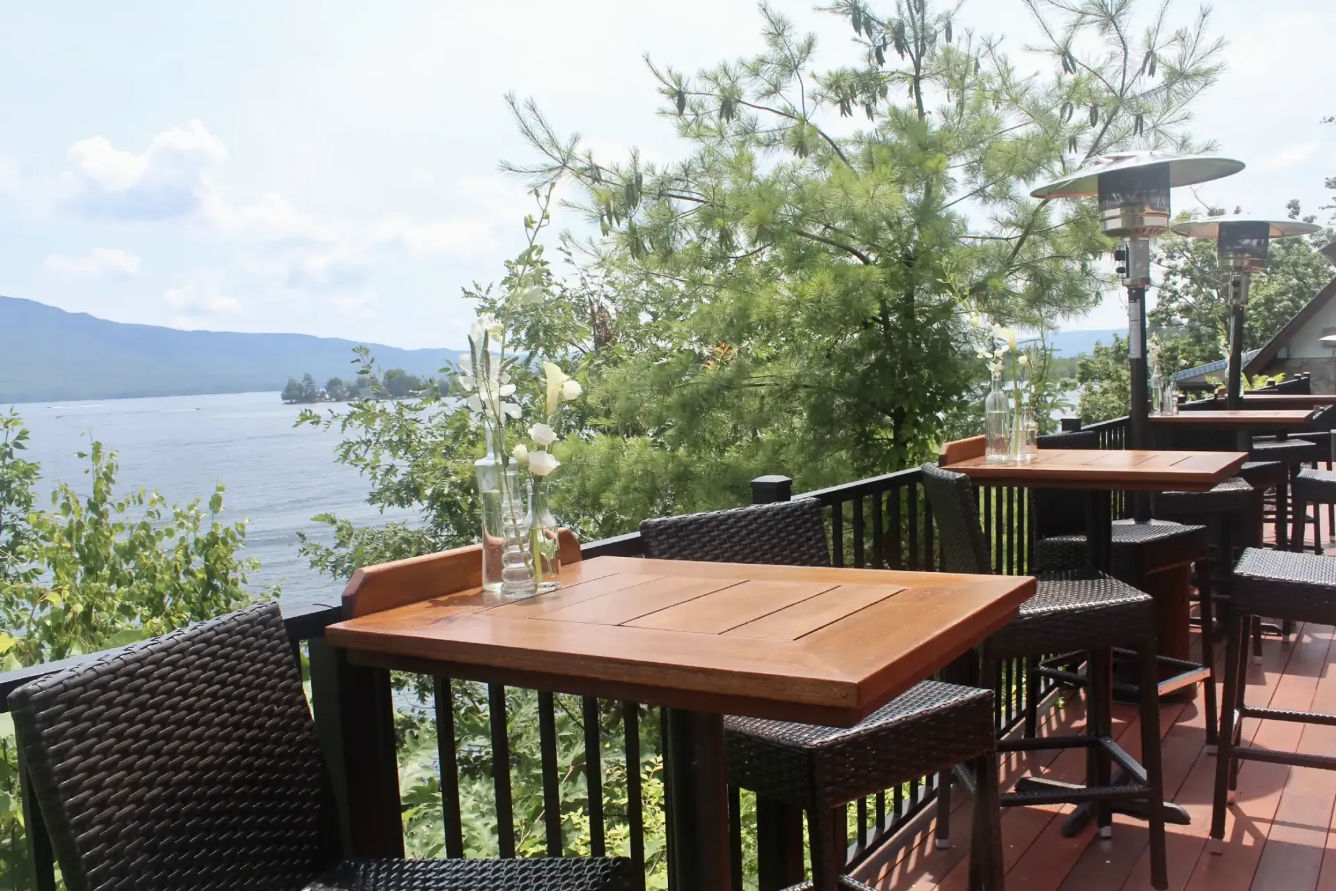 A patio with tables and chairs overlooking a lake