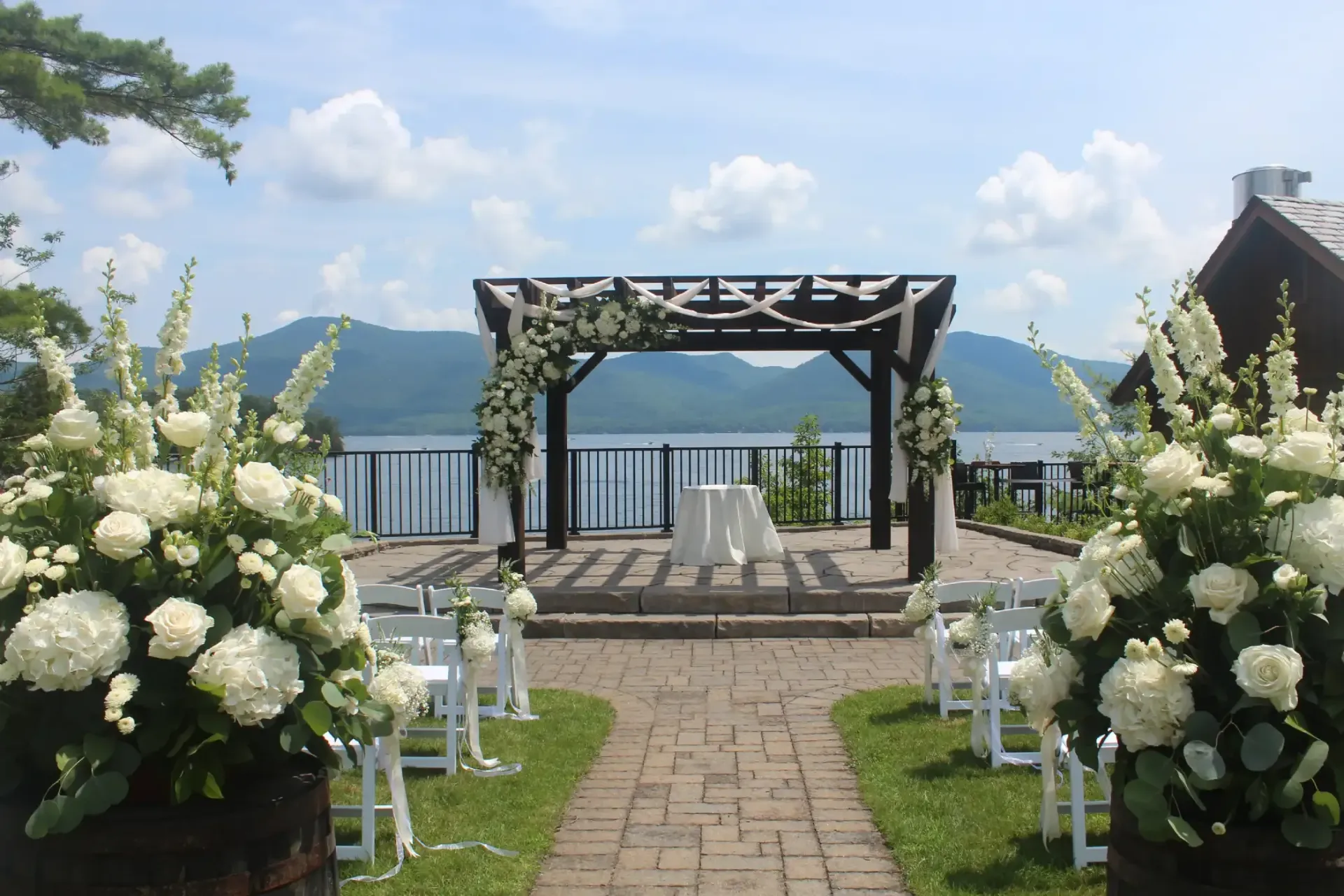 A wedding ceremony is taking place in front of a lake with mountains in the background.