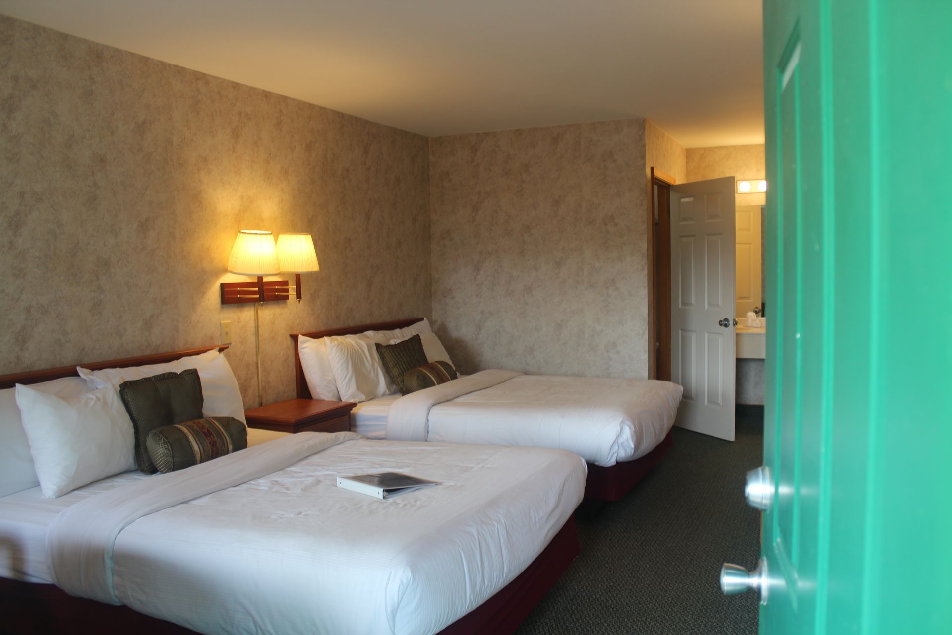 A hotel room with two beds and a green door
