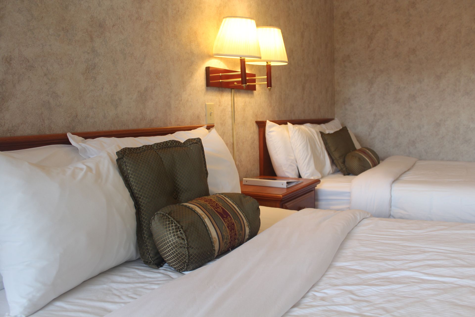 A hotel room with two beds and two lamps