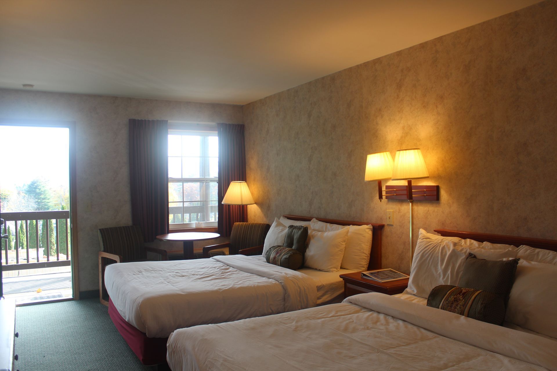 A hotel room with two beds and a balcony