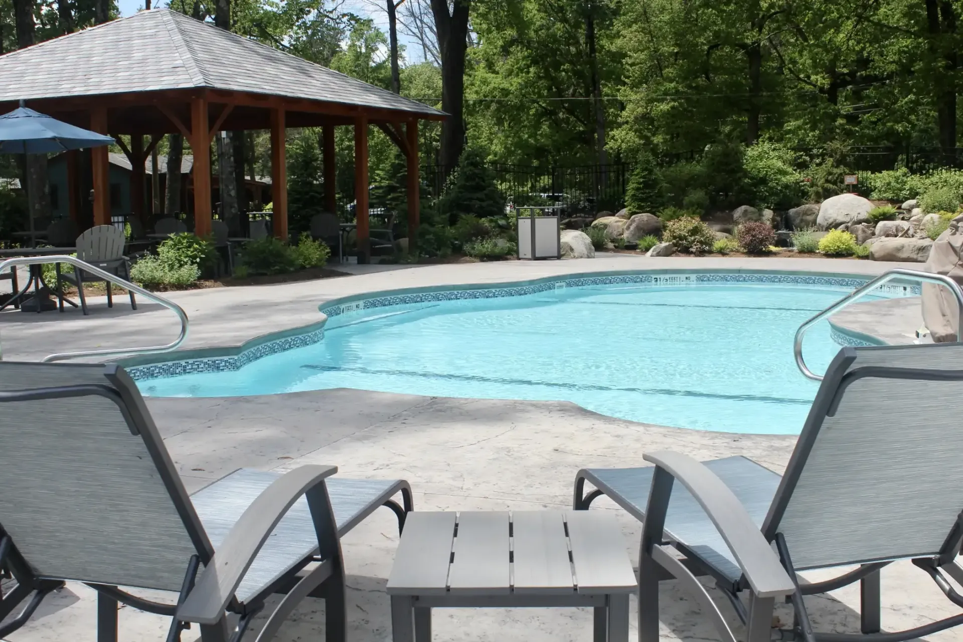 A large swimming pool with a gazebo in the background