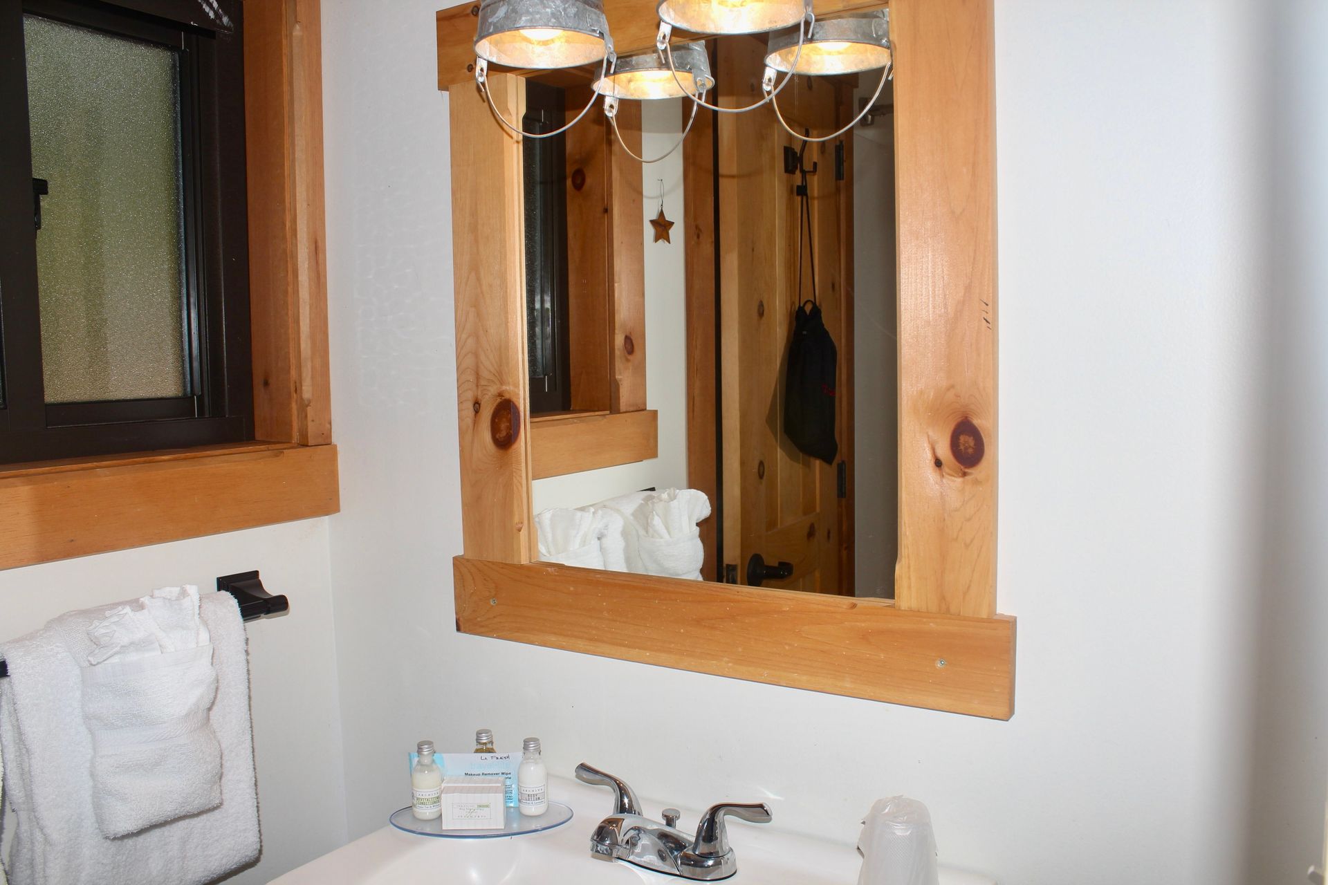 A bathroom with a sink , mirror and window