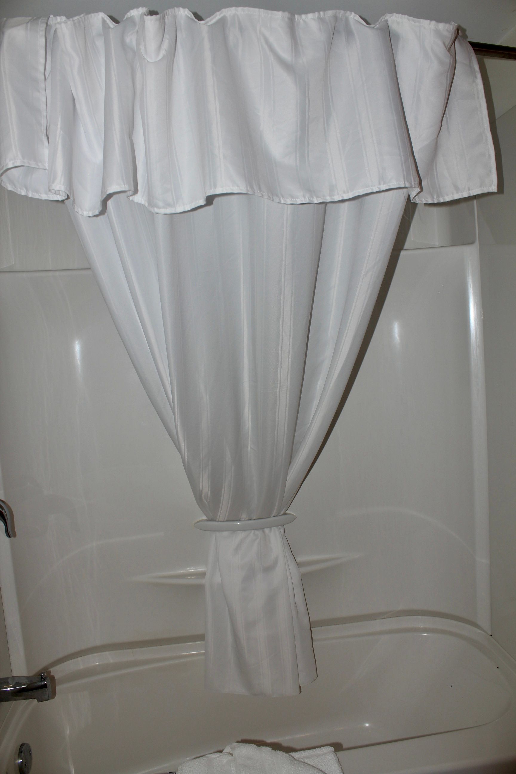 A white shower curtain is hanging over a bathtub.