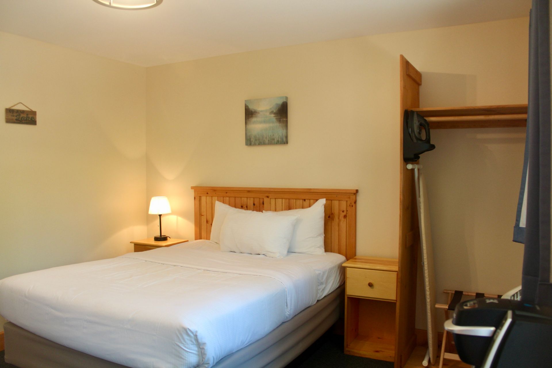 A hotel room with a bed , nightstand , television and a sign that says welcome.