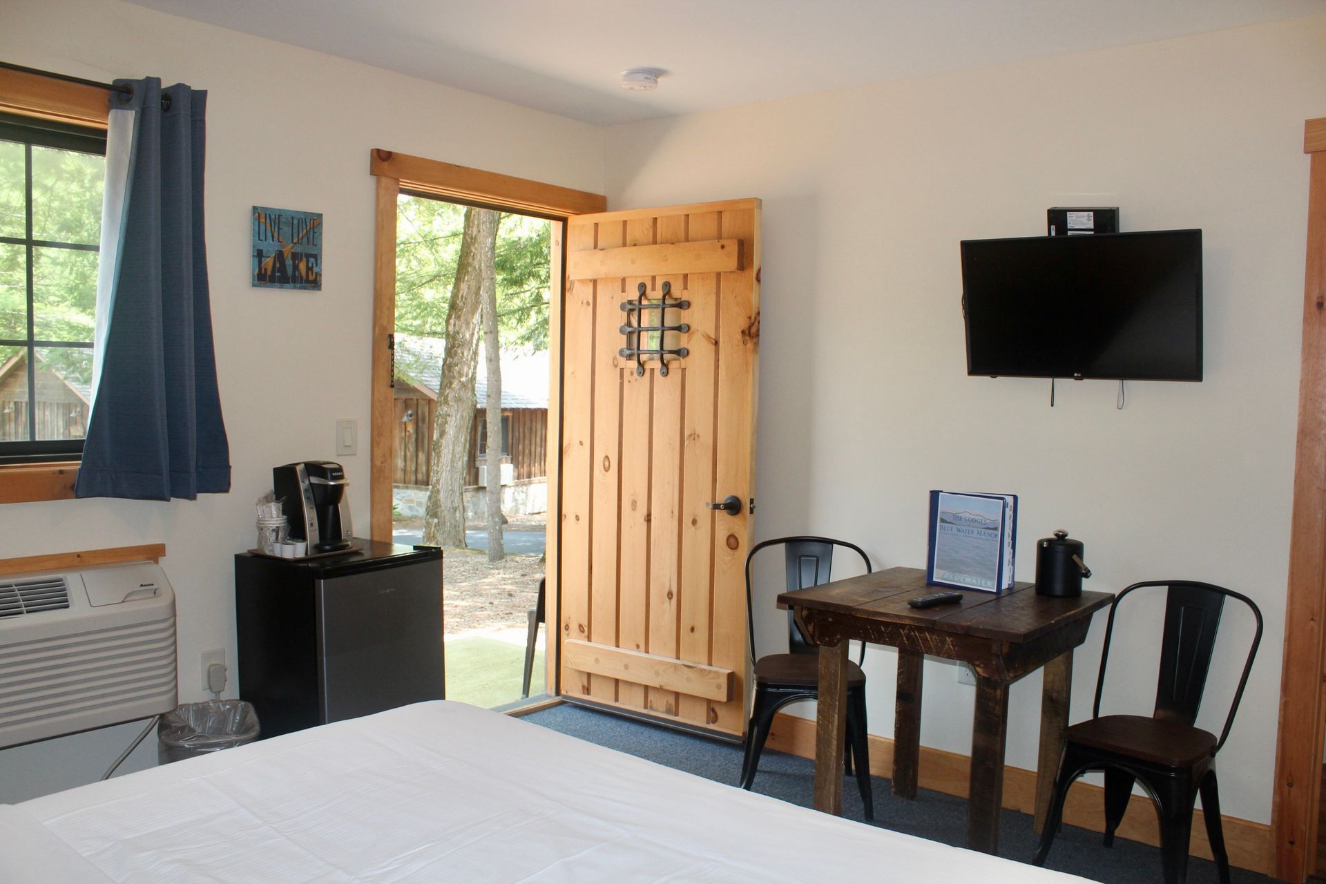 A hotel room with a table and chairs and a flat screen tv