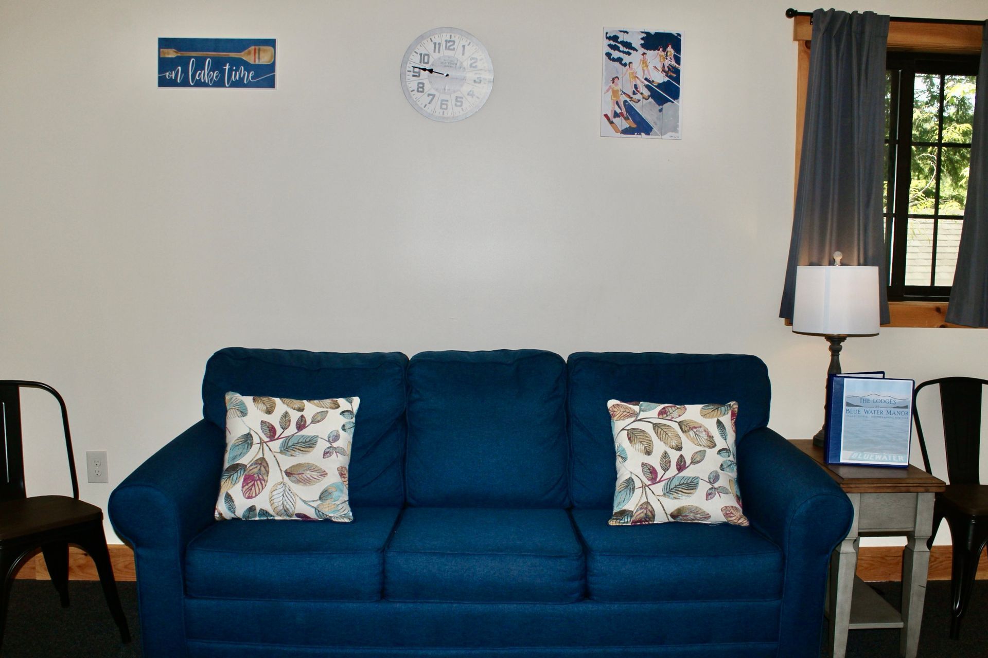 A living room with a blue couch and a clock on the wall