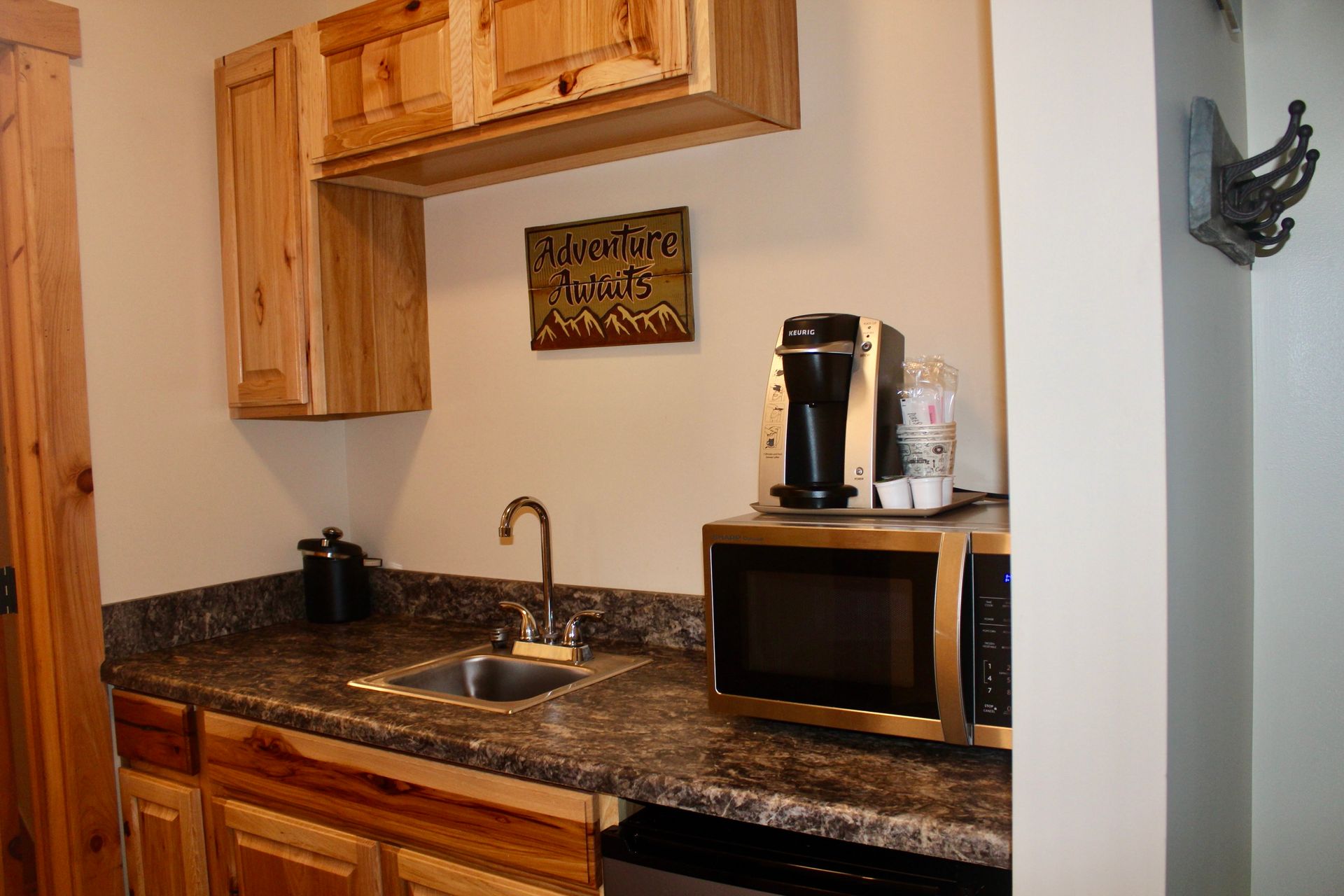 A small kitchen with a sink , microwave , and coffee maker.