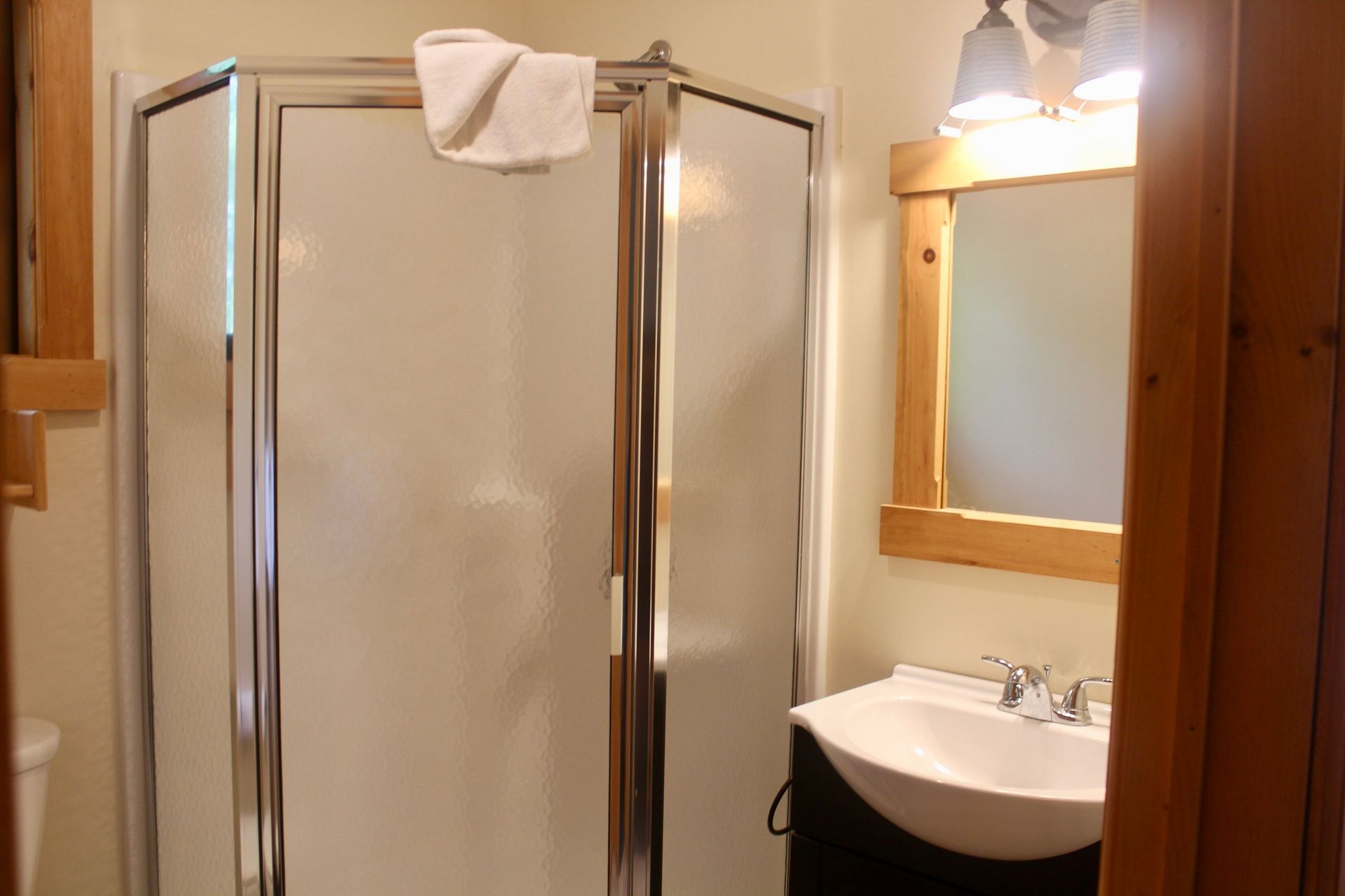 A bathroom with a sink , shower and mirror.