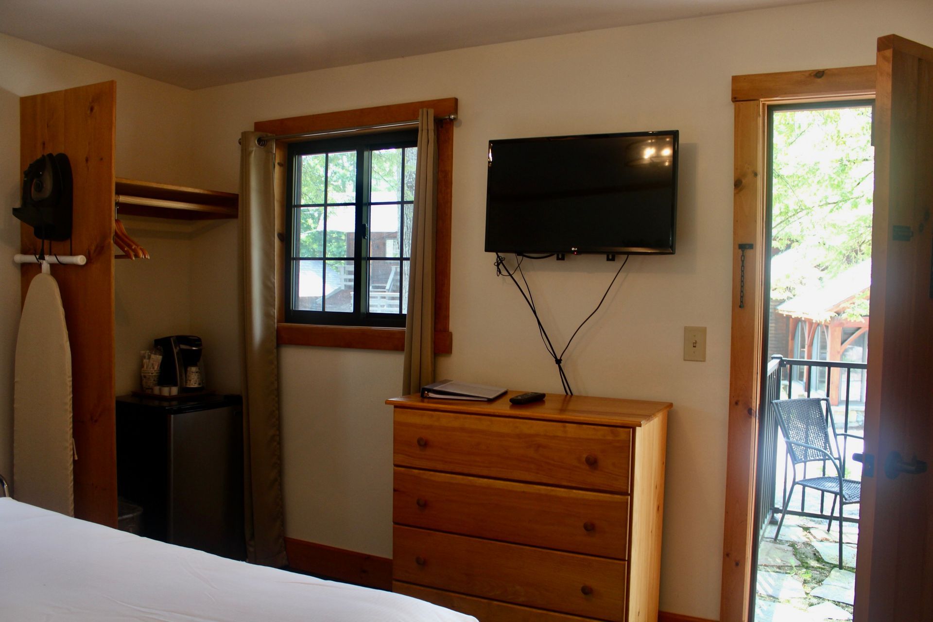 A bedroom with a dresser and a flat screen tv on the wall.