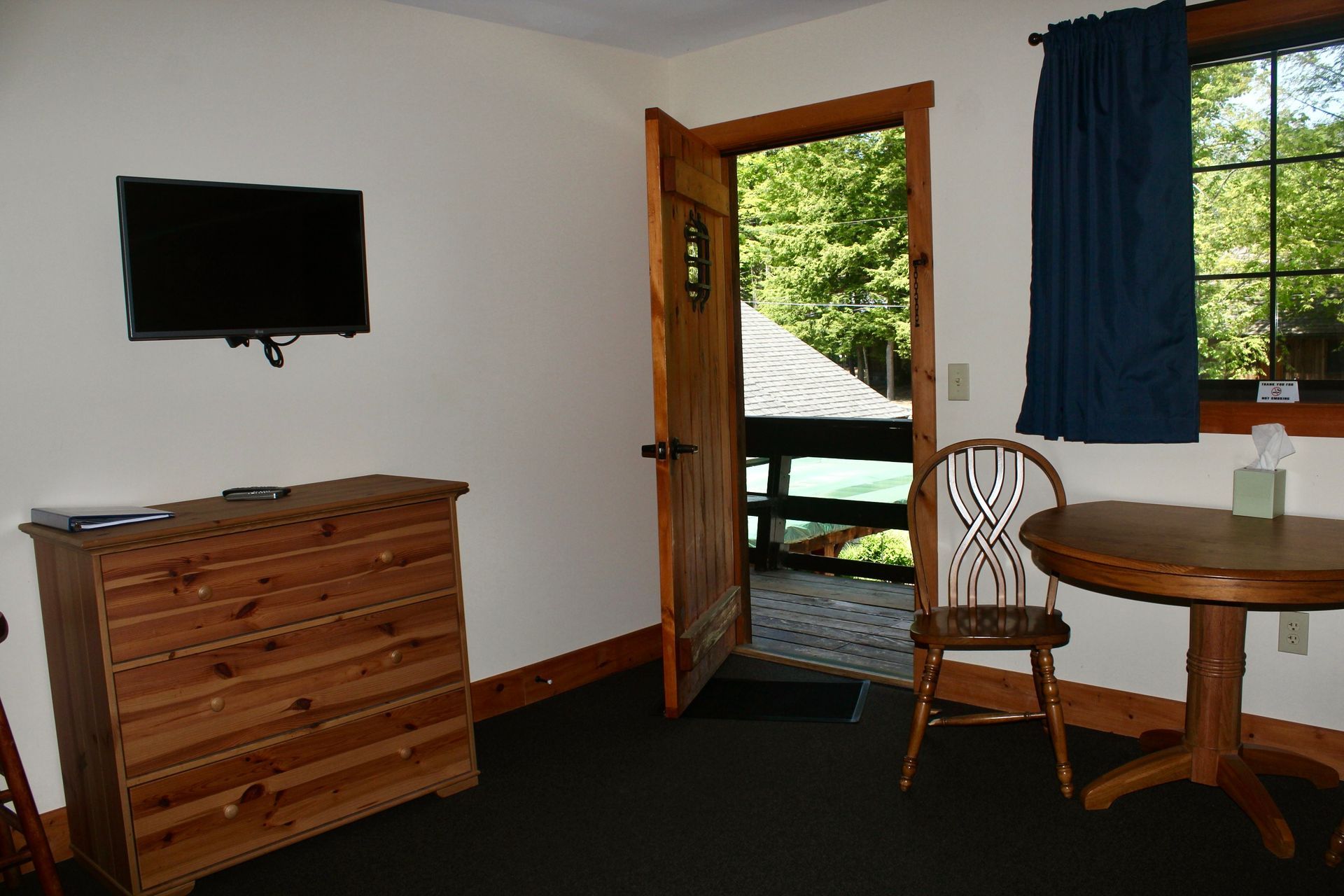 A living room with a table , chair , dresser and television
