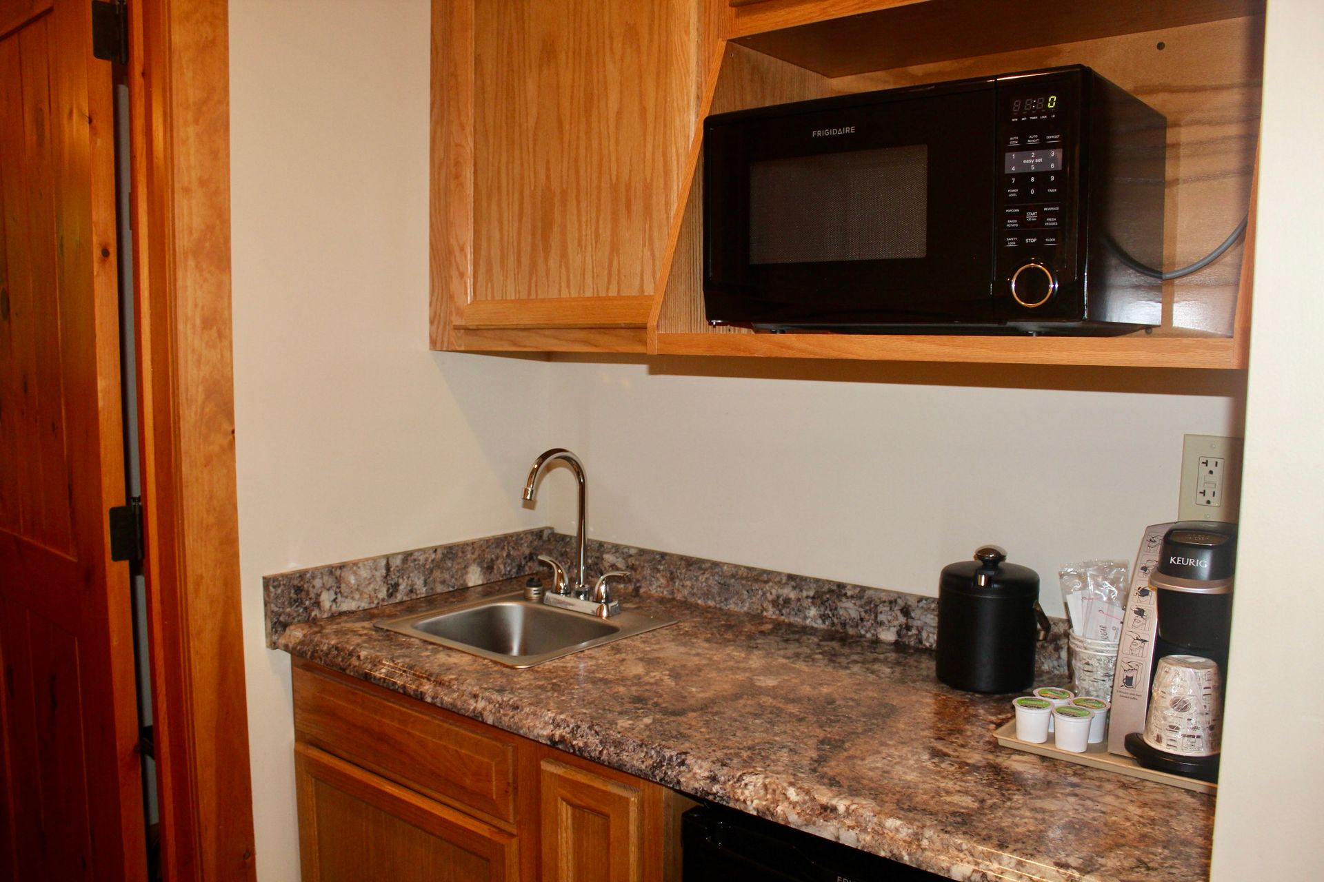 A kitchen with a sink , microwave , and coffee maker.