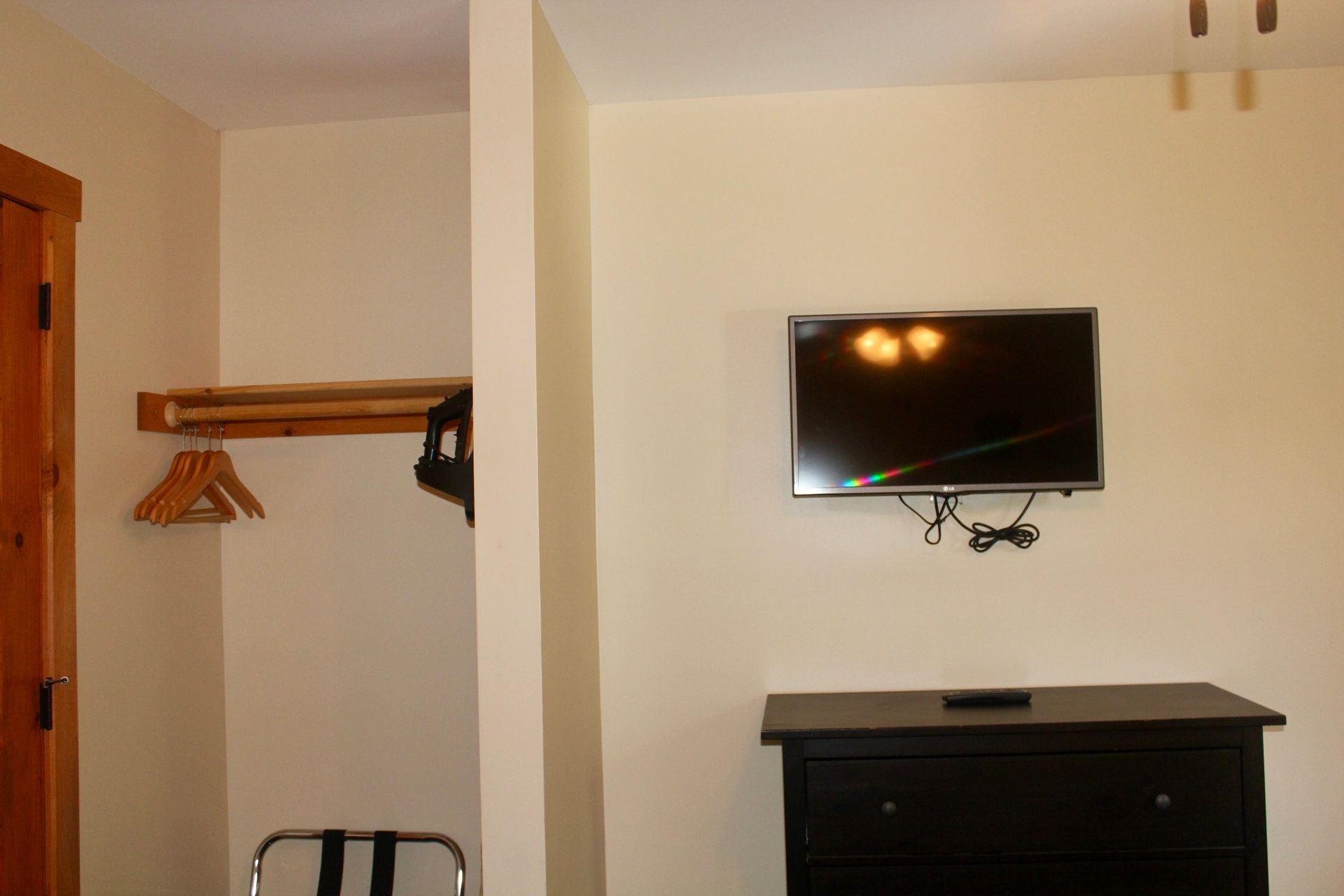 A room with a dresser and a flat screen tv on the wall.