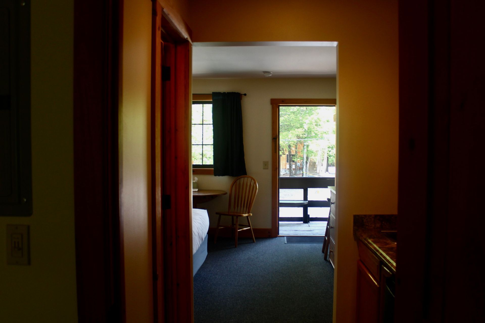 A hotel room with a bed , chair , desk and sliding glass door.