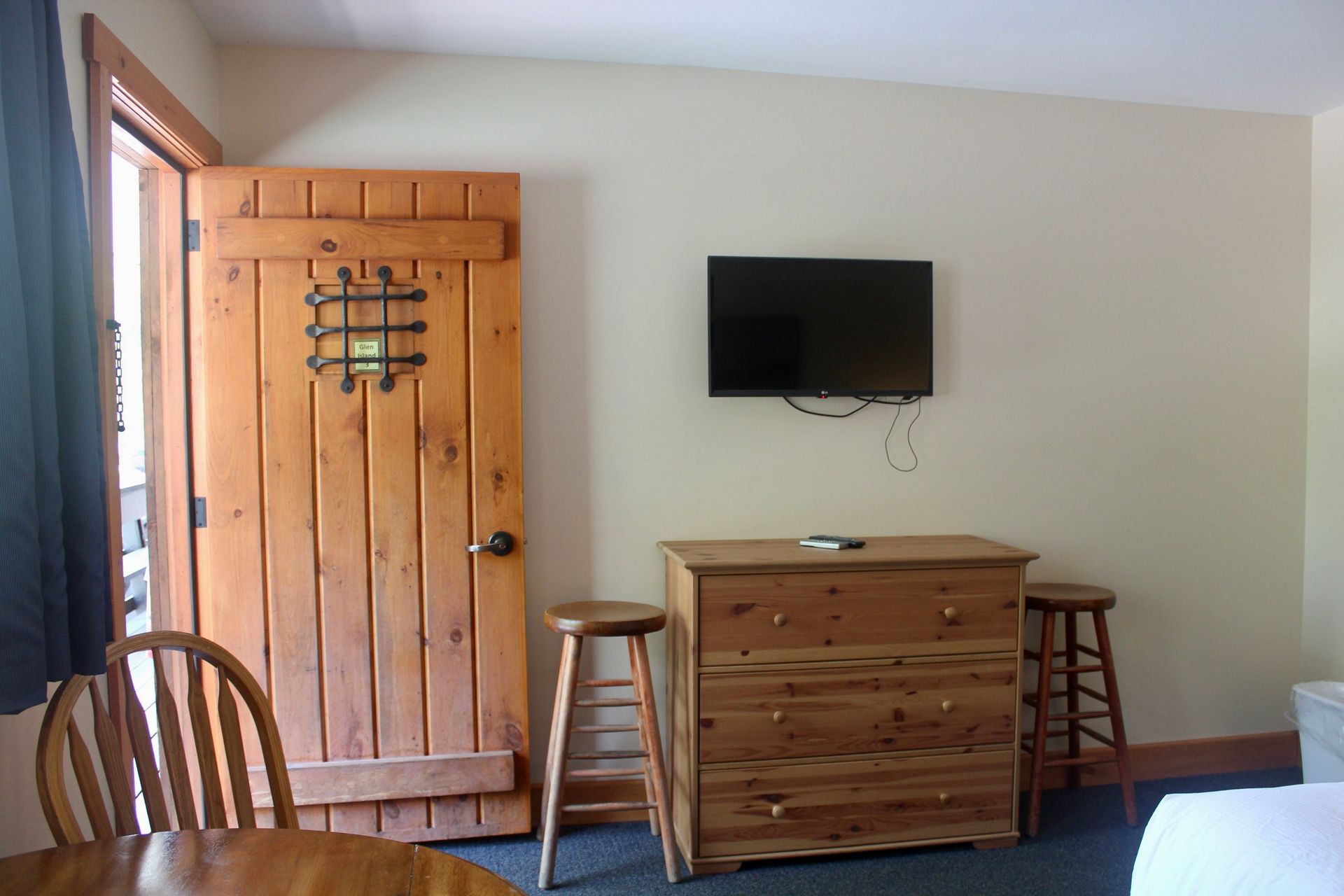 A bedroom with a wooden door a dresser and a flat screen tv