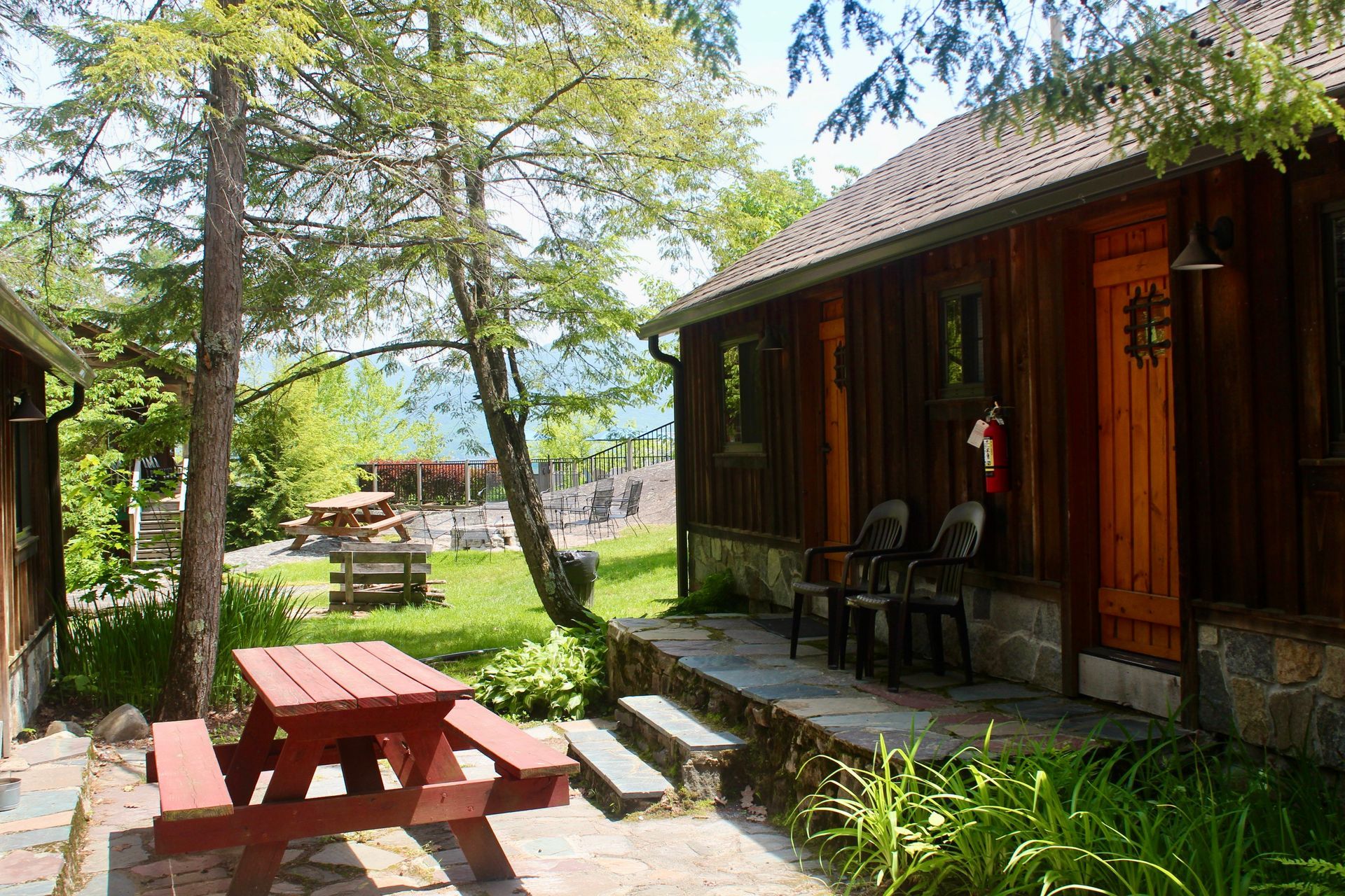 A wooden cabin with a picnic table and chairs in front of it.