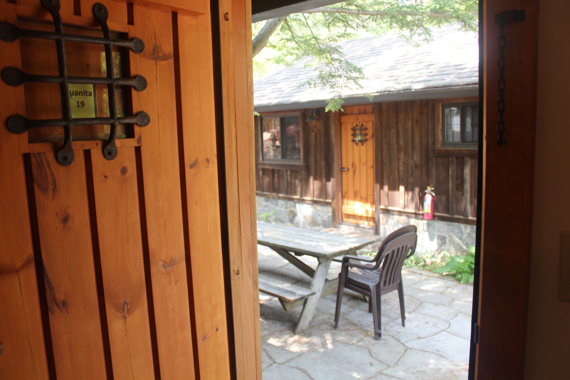 A wooden door open to a patio with a picnic table and chairs