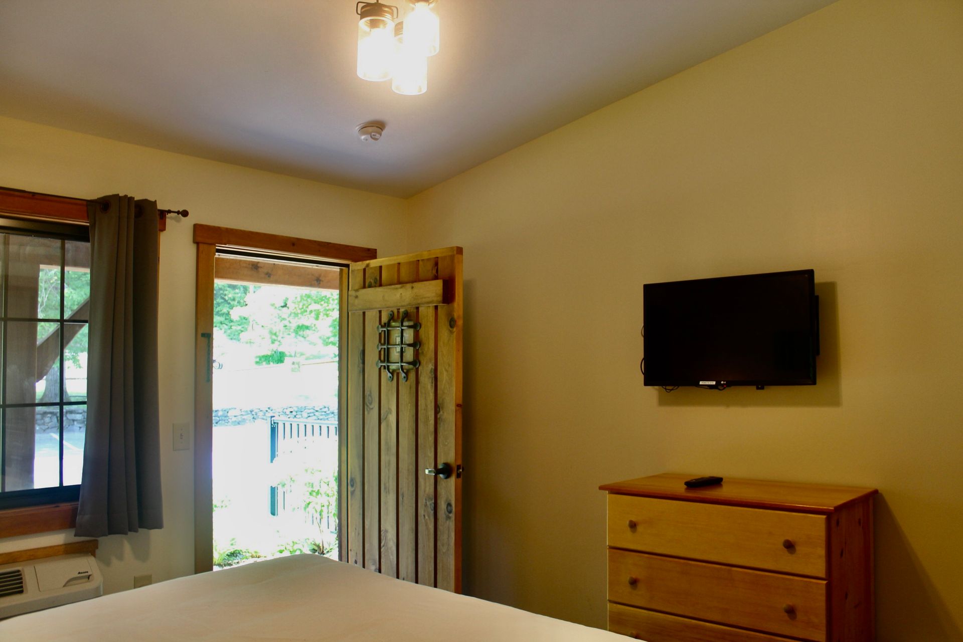 A bedroom with a bed , dresser and television.