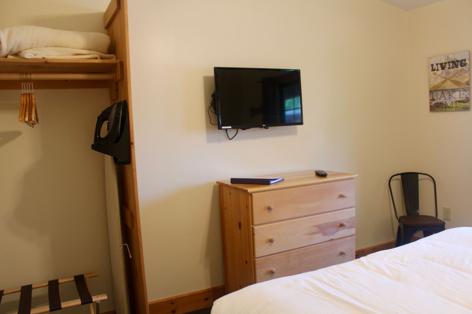 A bedroom with a bed , dresser and television on the wall.