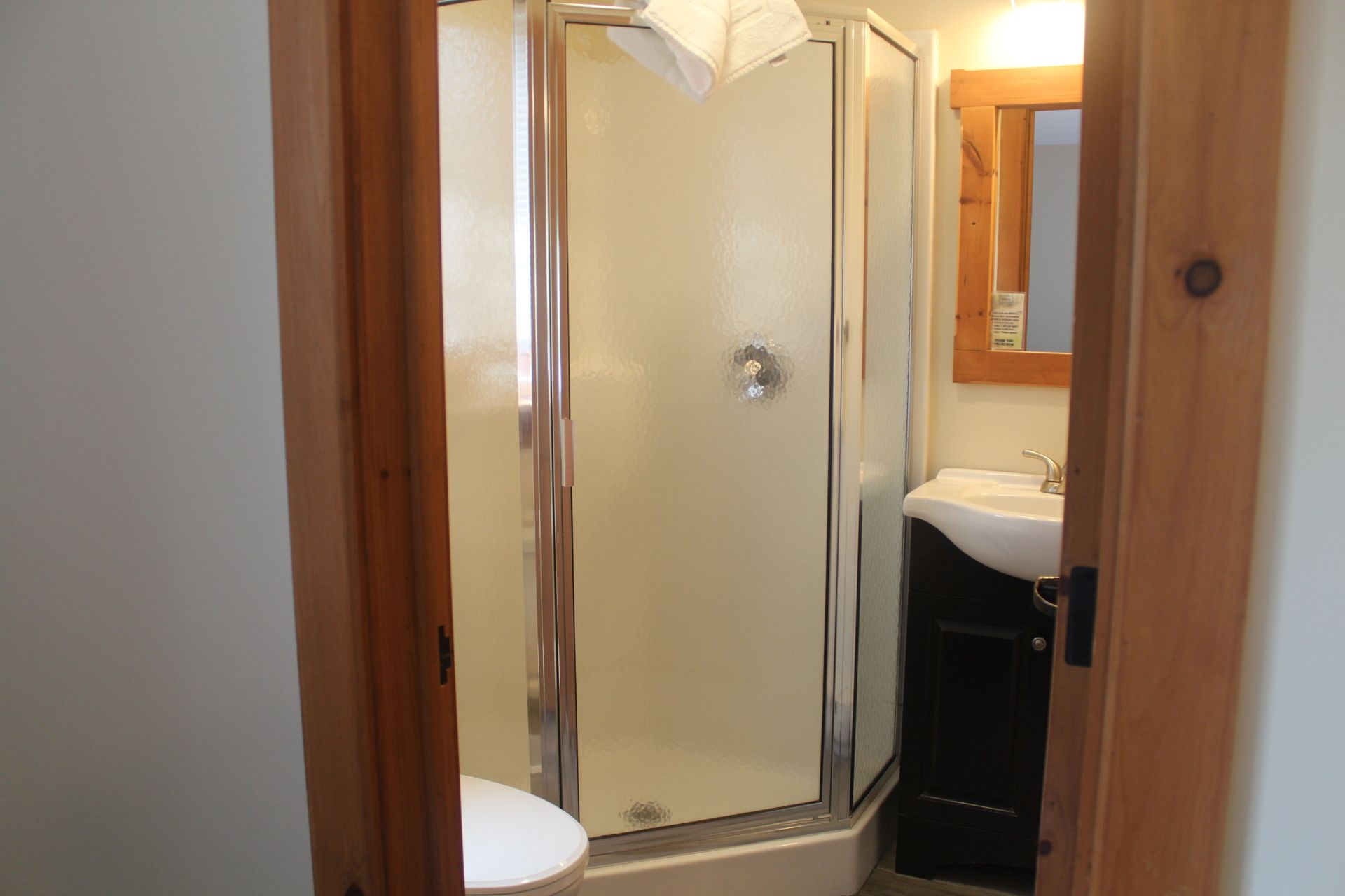 A bathroom with a shower , sink and mirror.