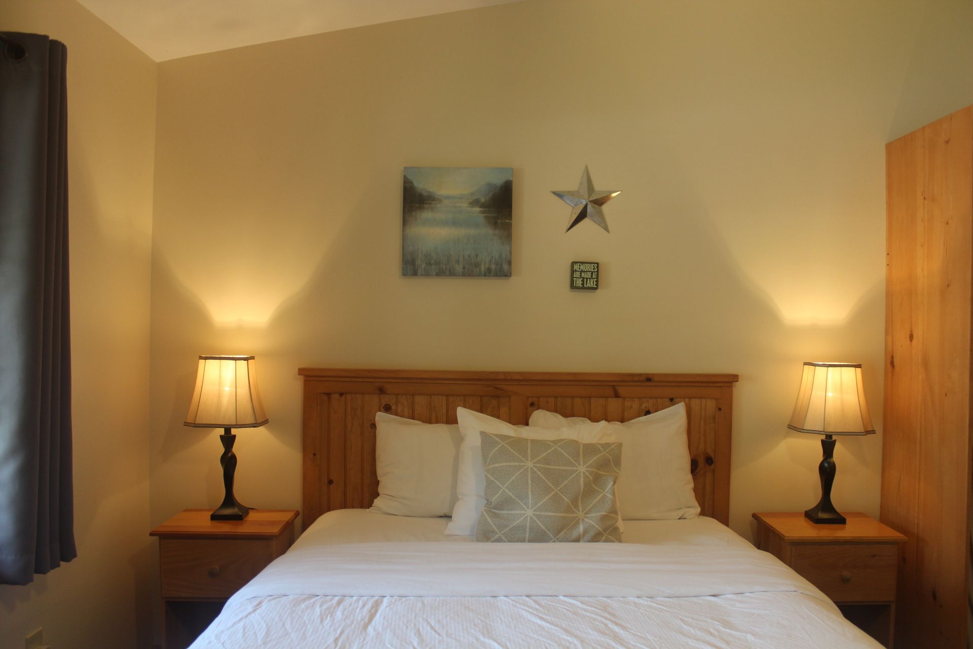 A bedroom with a bed , nightstands , lamps and a painting on the wall.
