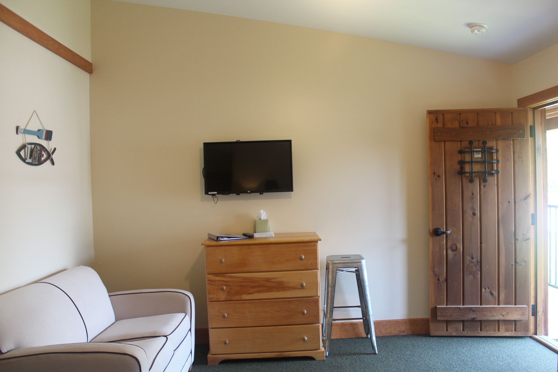 A living room with a couch , dresser and television on the wall.