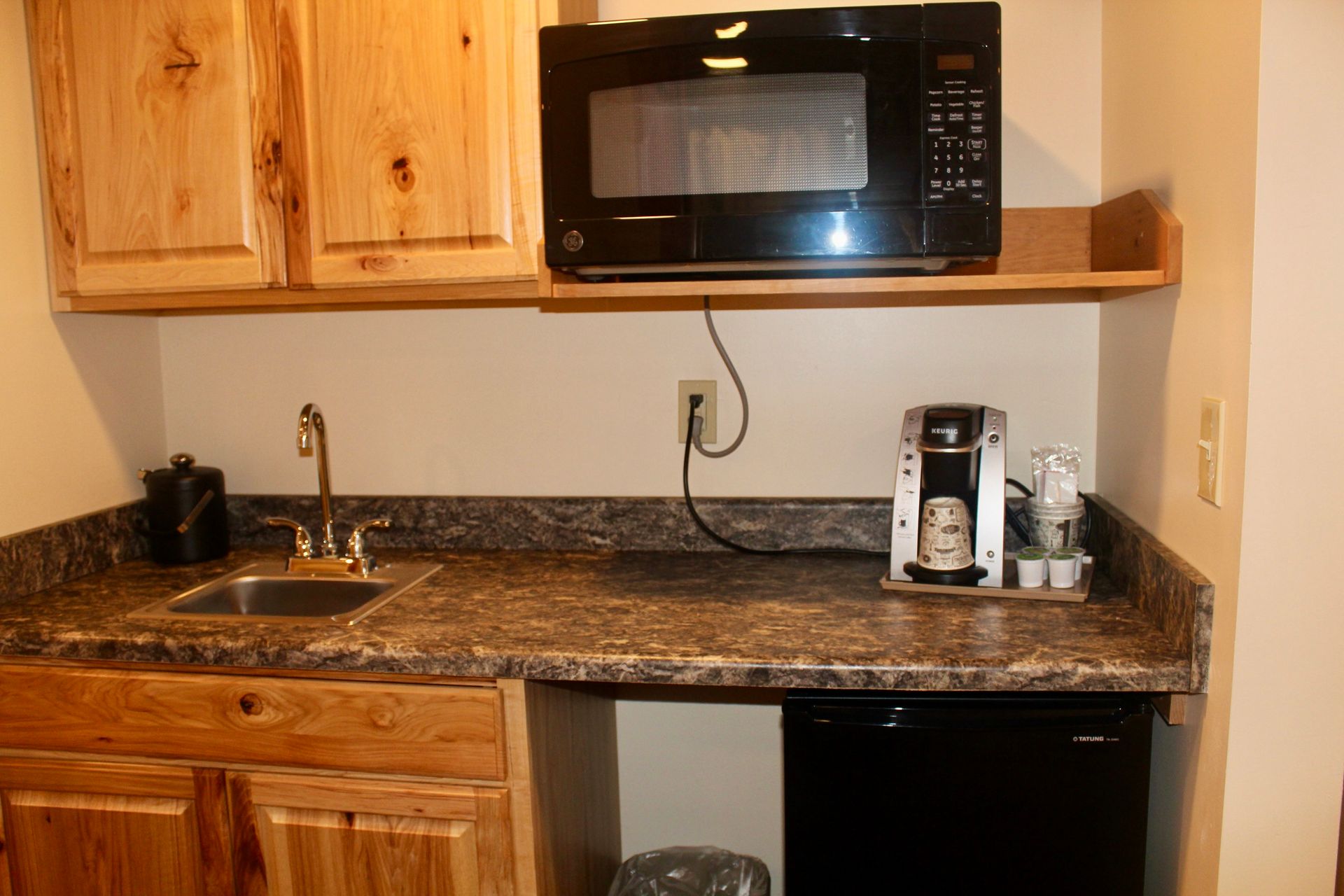A kitchen with a sink , microwave , coffee maker and dishwasher.