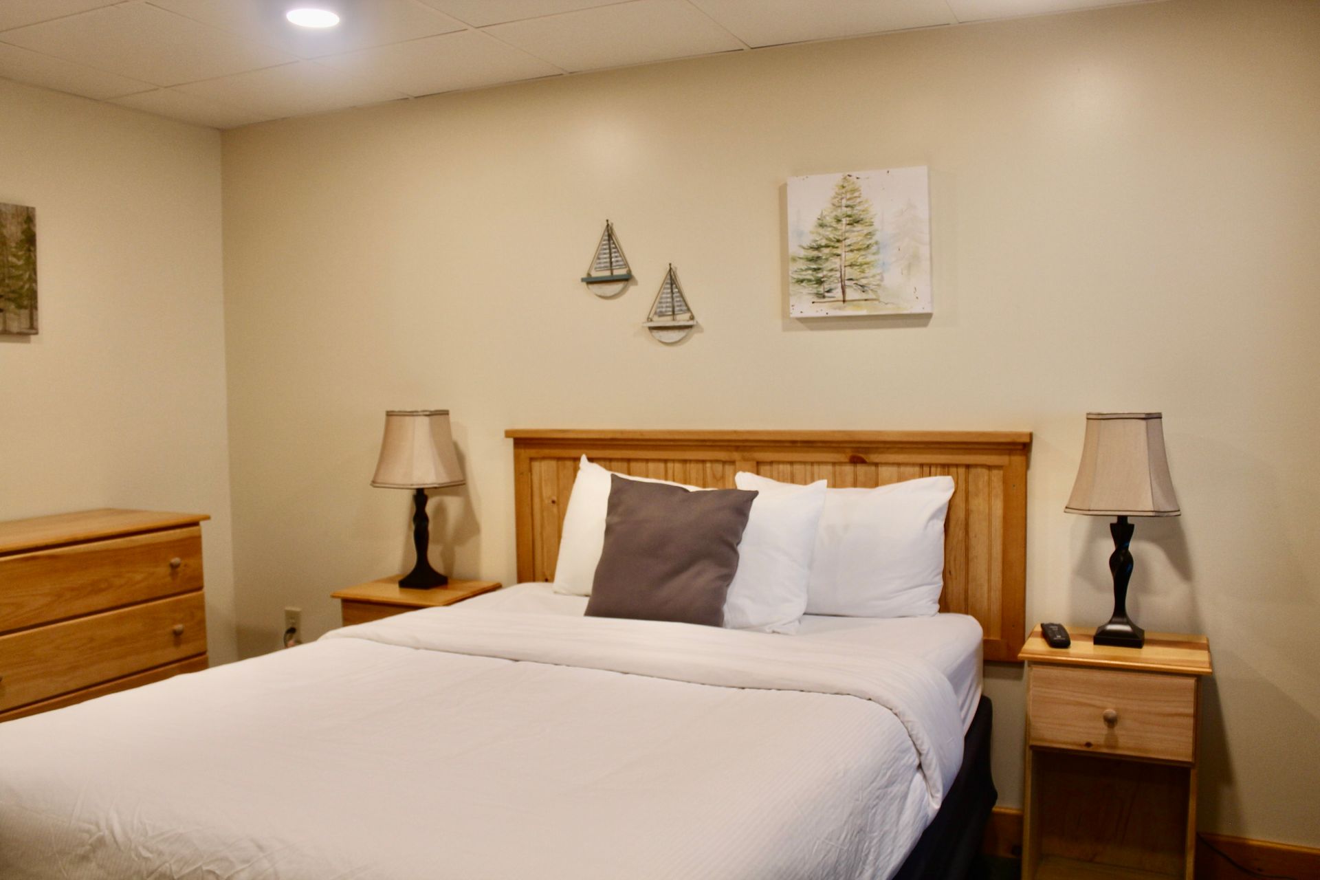 A bedroom with a bed , nightstands , lamps and a dresser.