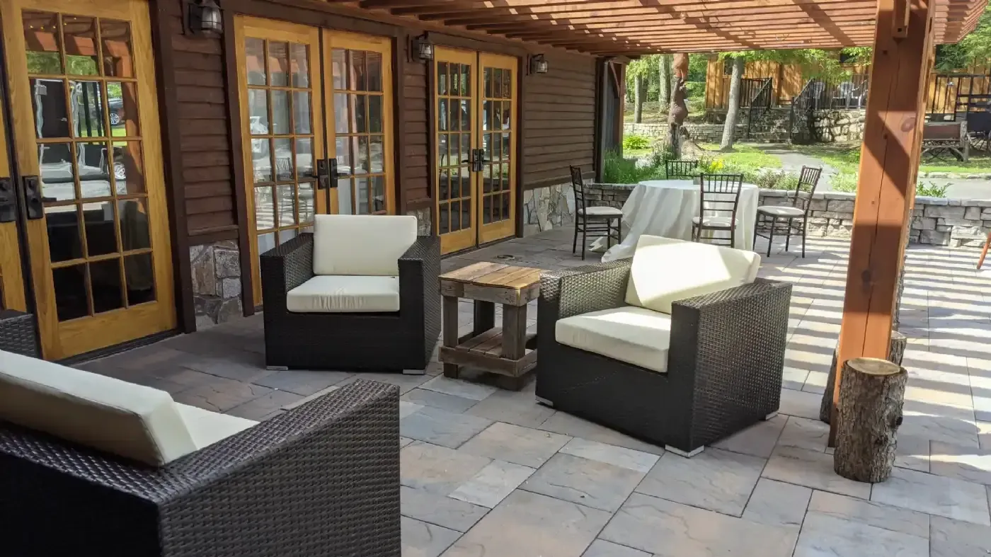 A patio with chairs and a table under a pergola.
