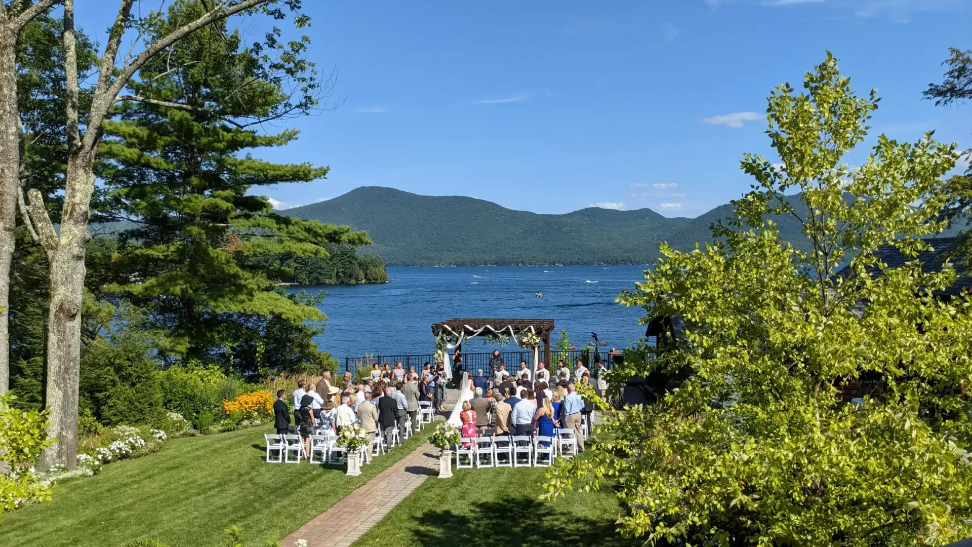 A large group of people are sitting in chairs in front of a lake.