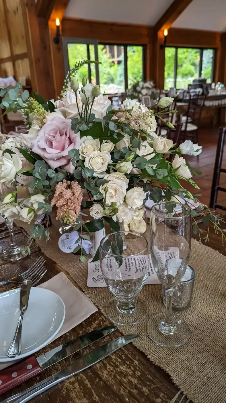 A table set for a wedding reception with a vase of flowers on it.
