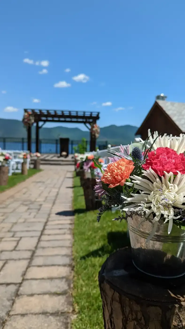 A row of buckets filled with flowers are lined up on a sidewalk.