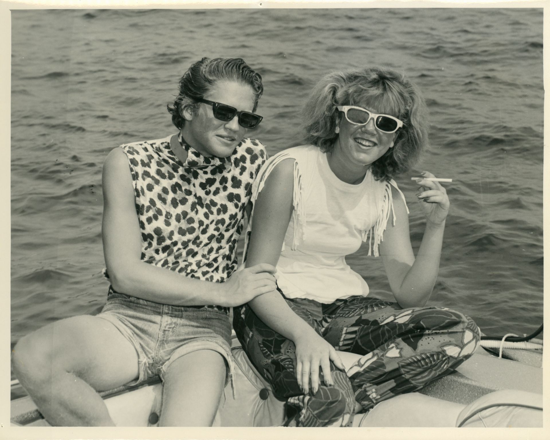 Two women wearing sunglasses are sitting on a boat in the water