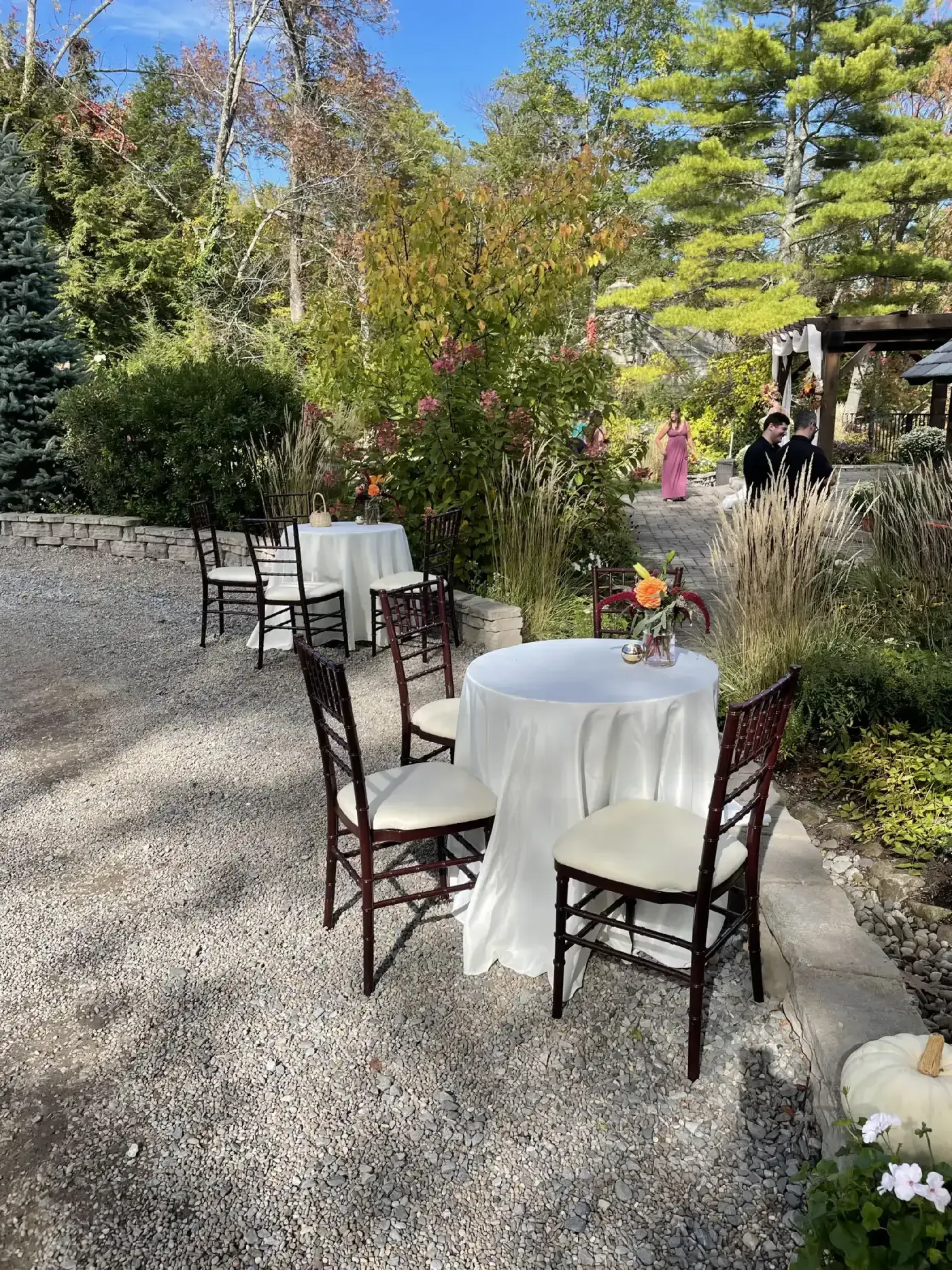 A group of tables and chairs sitting on top of a gravel driveway.