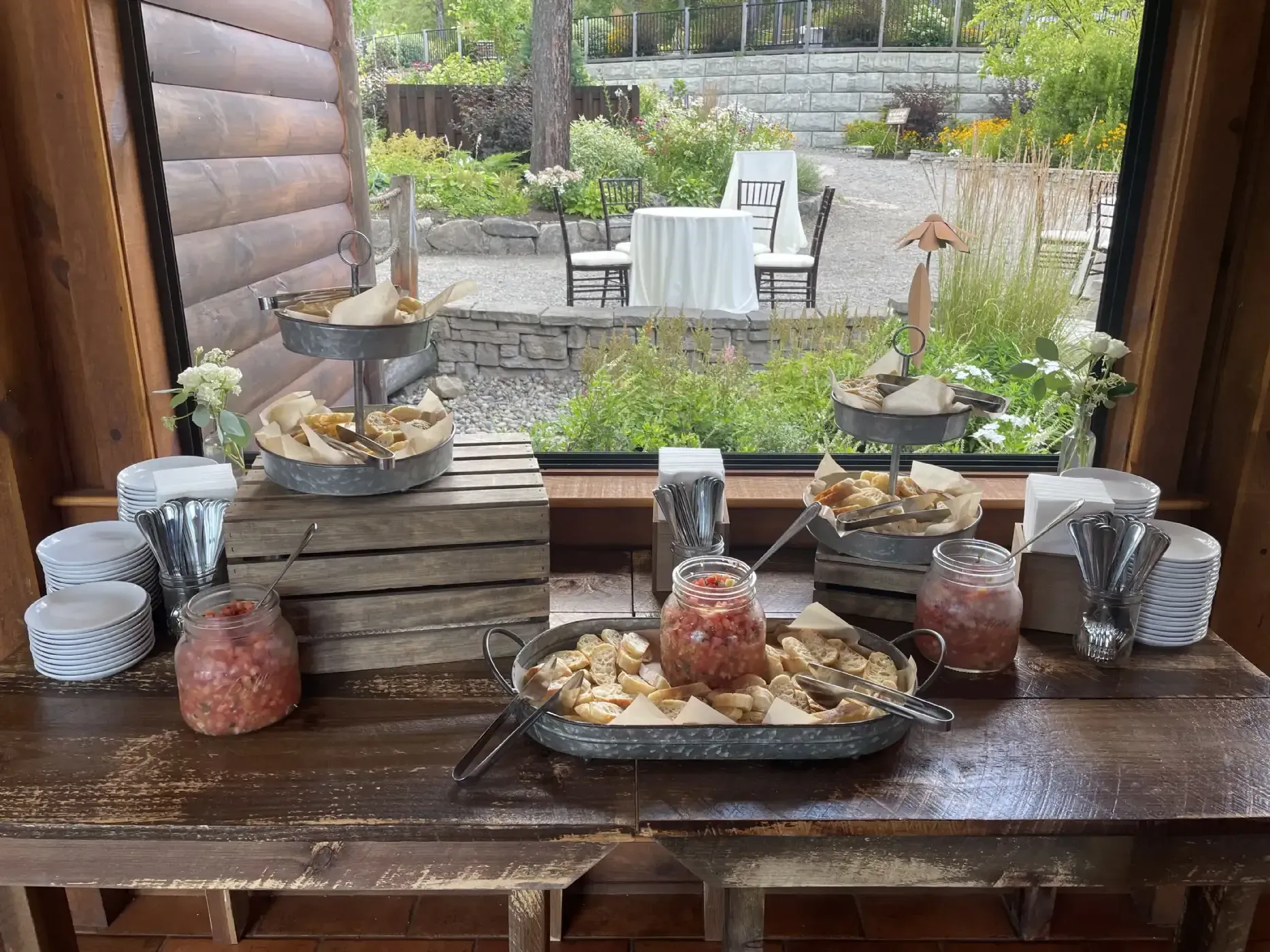 A wooden table with a variety of food on it in front of a window.