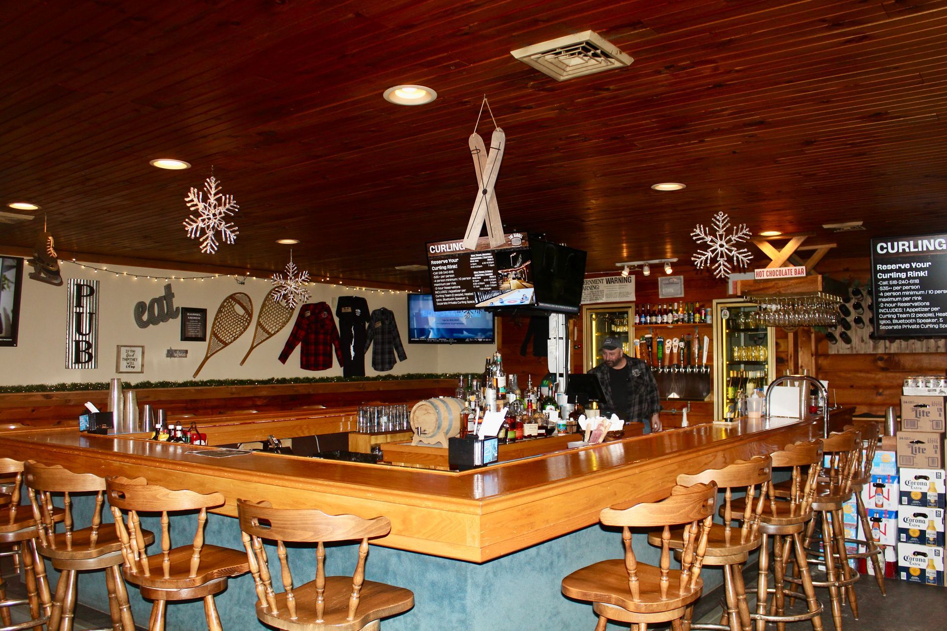 A bar in a restaurant with skis hanging from the ceiling