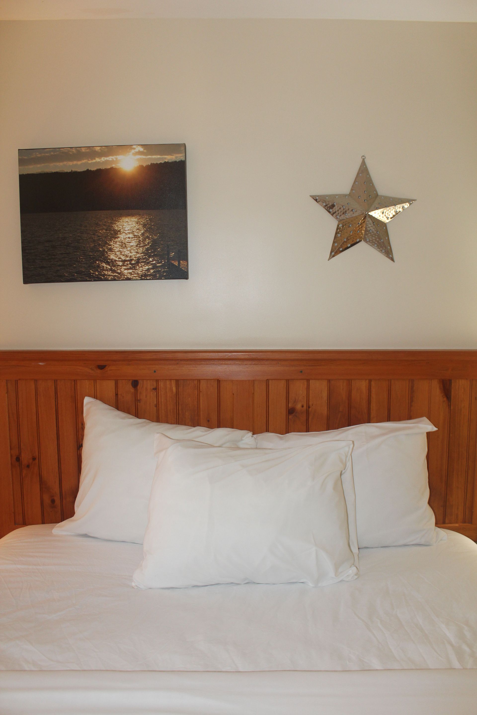 A bed with white sheets and a star on the wall above it