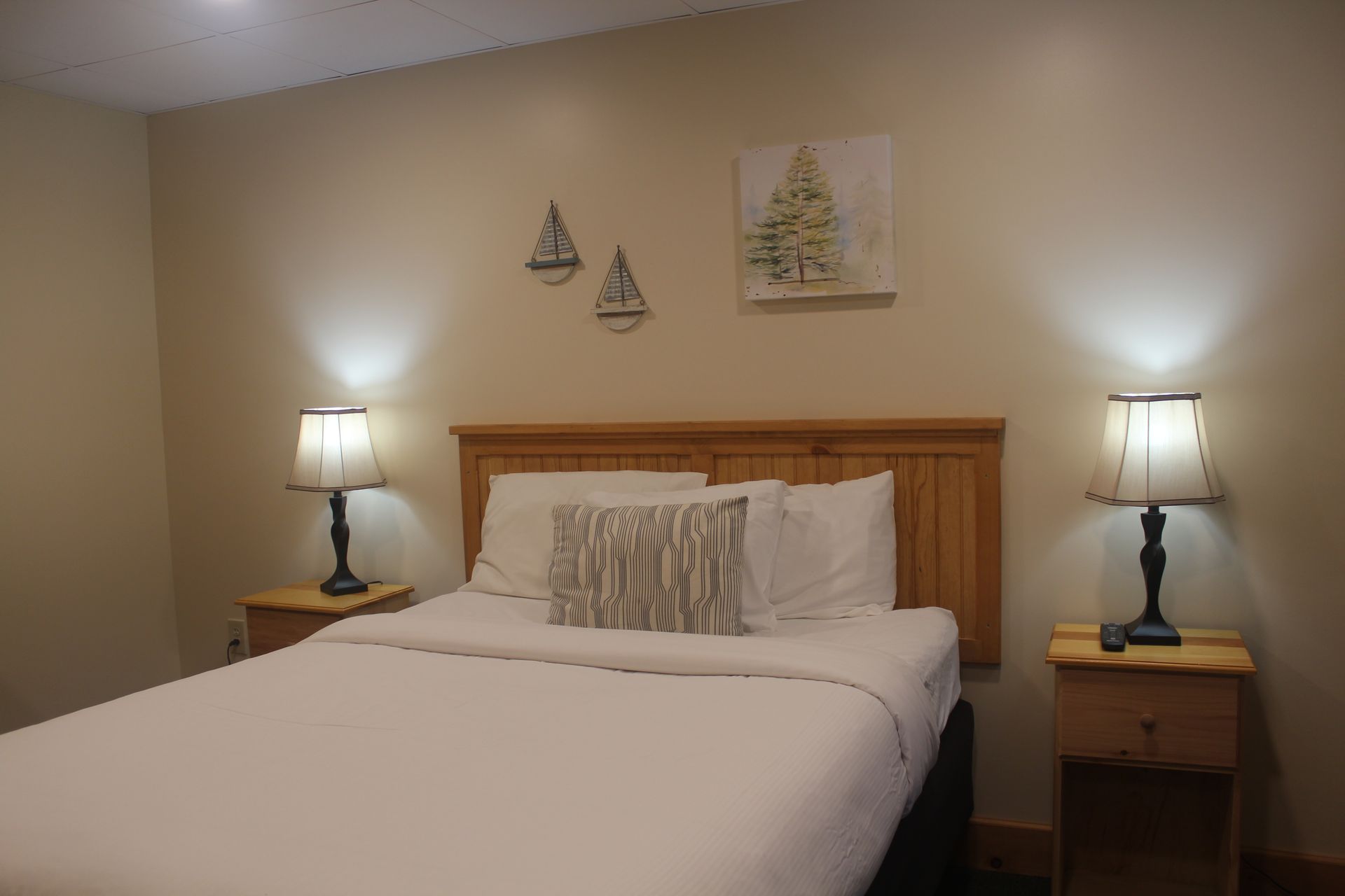 A bedroom with a bed , nightstands , lamps and a picture on the wall.