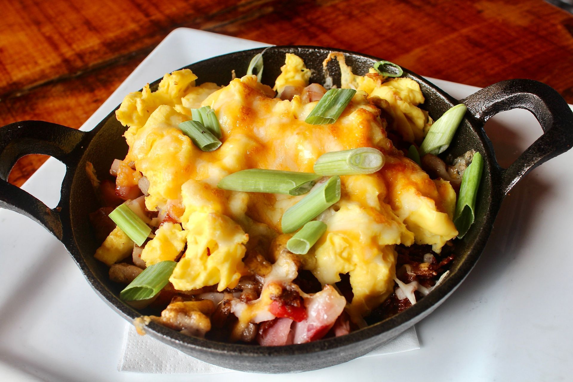 A skillet filled with scrambled eggs cheese and green onions