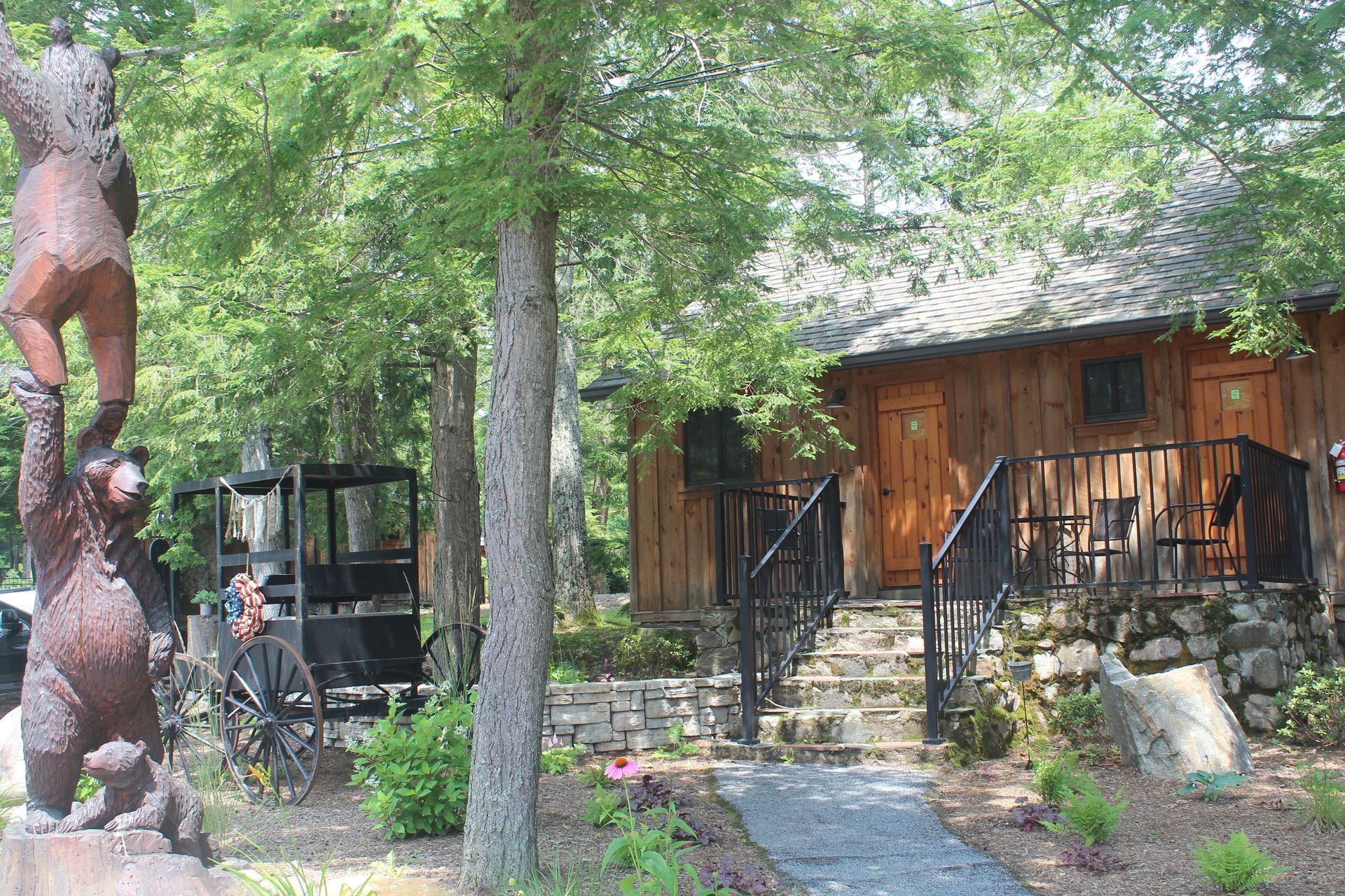 A statue of a bear is standing in front of a wooden cabin.