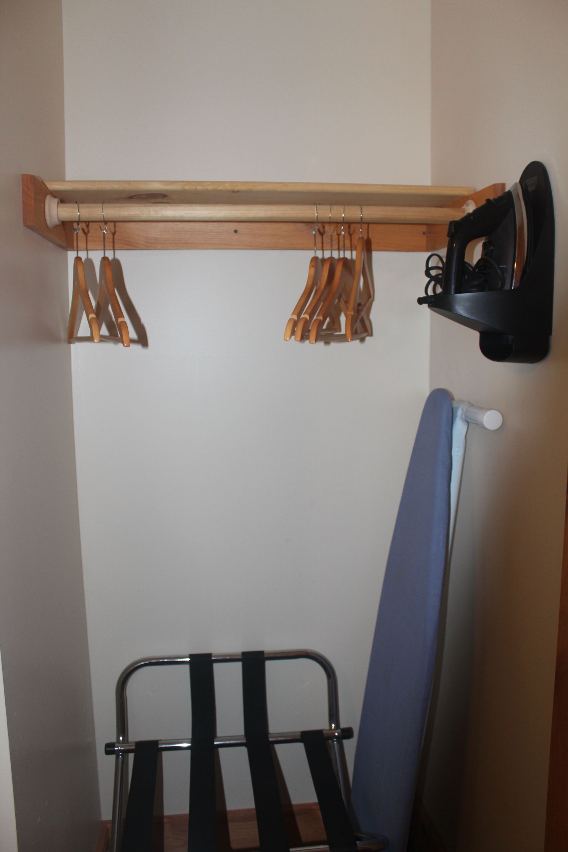 A closet with clothes hangers and an ironing board