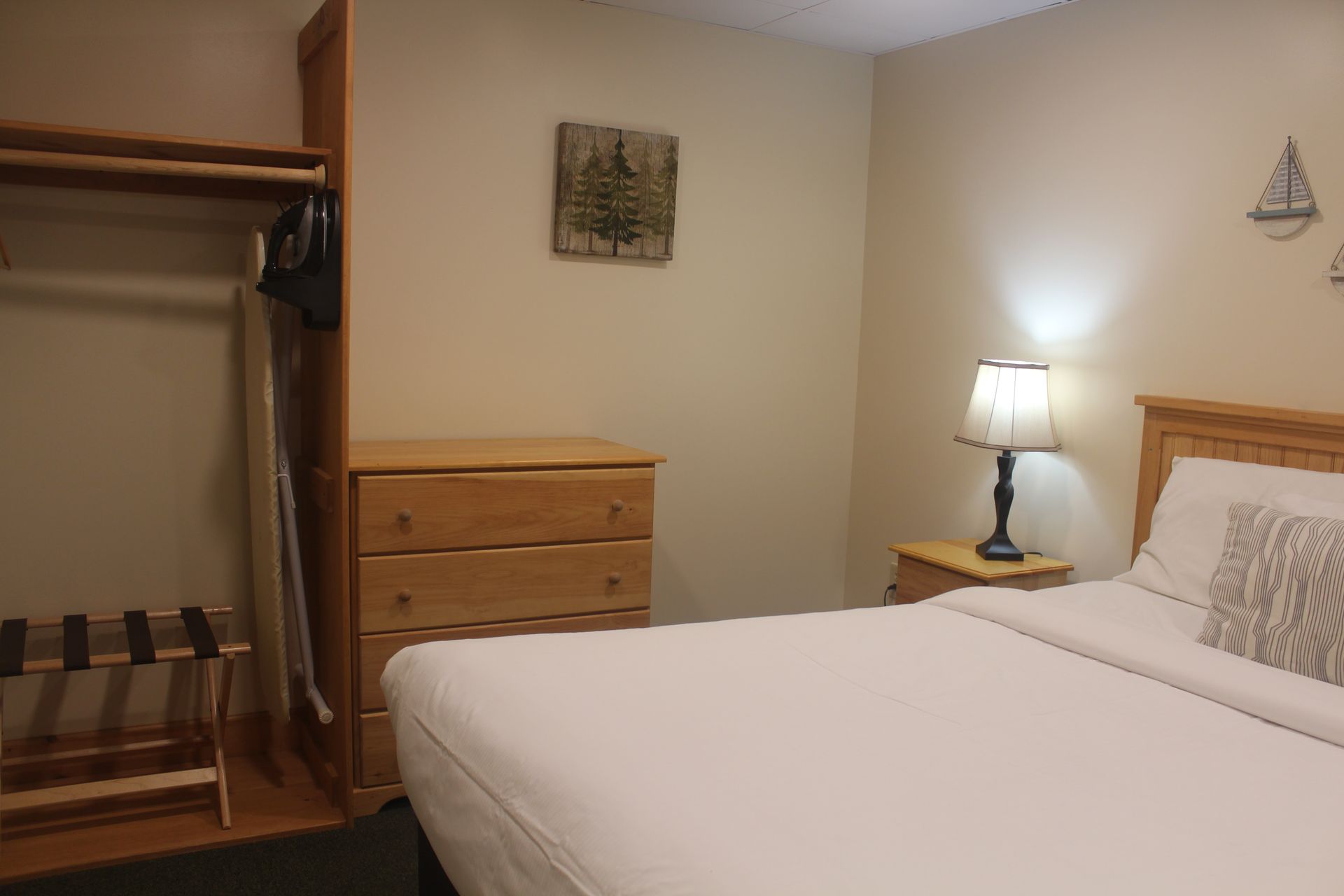 A bedroom with a bed , dresser , nightstand and lamp.