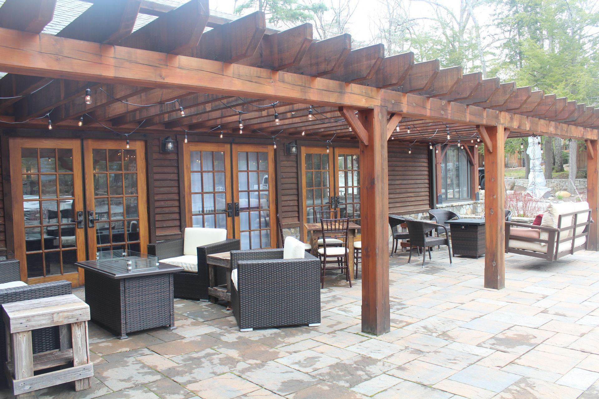 A wooden pergola over a patio with furniture