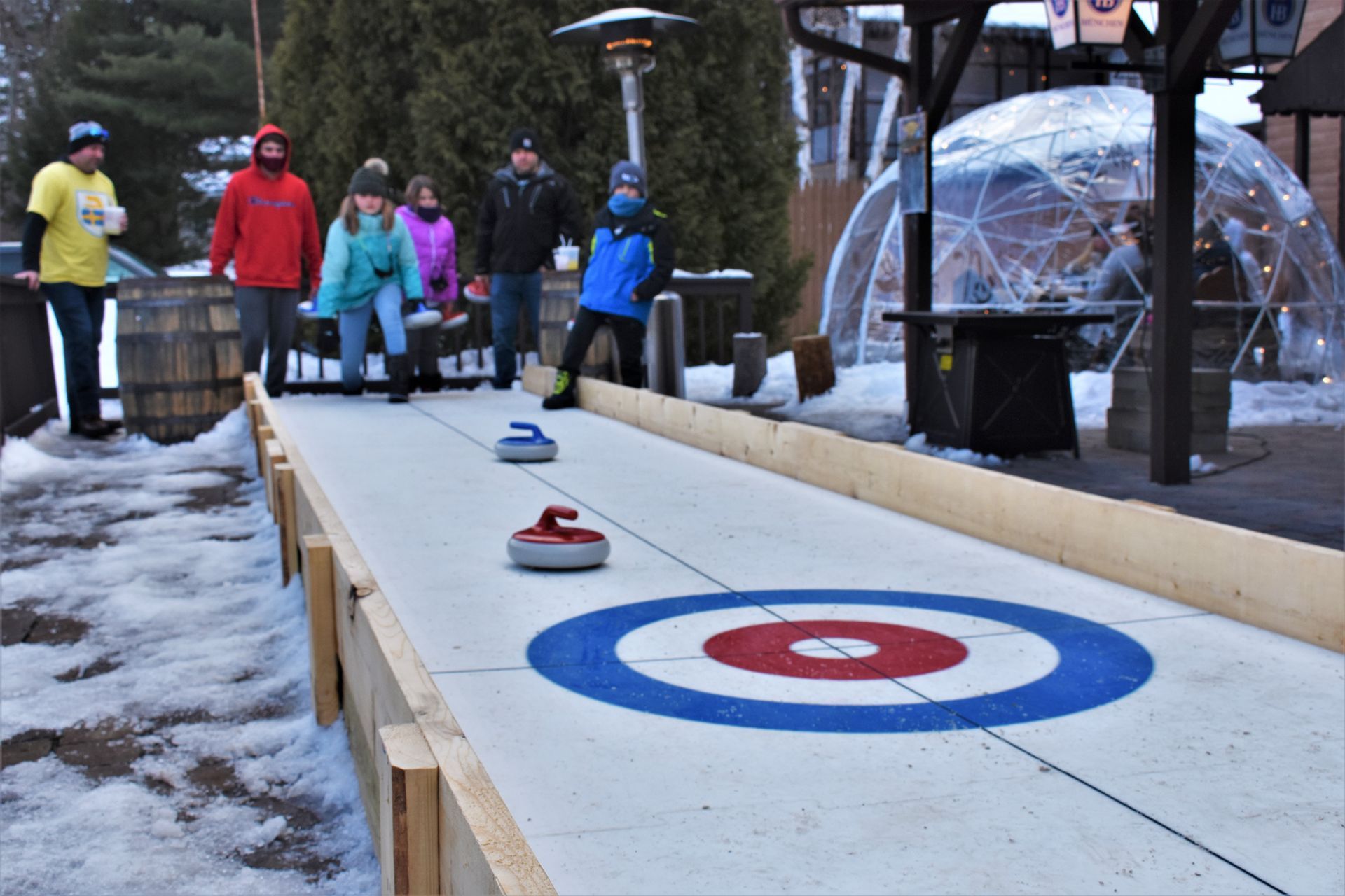A group of people are playing curling on a snowy rink.